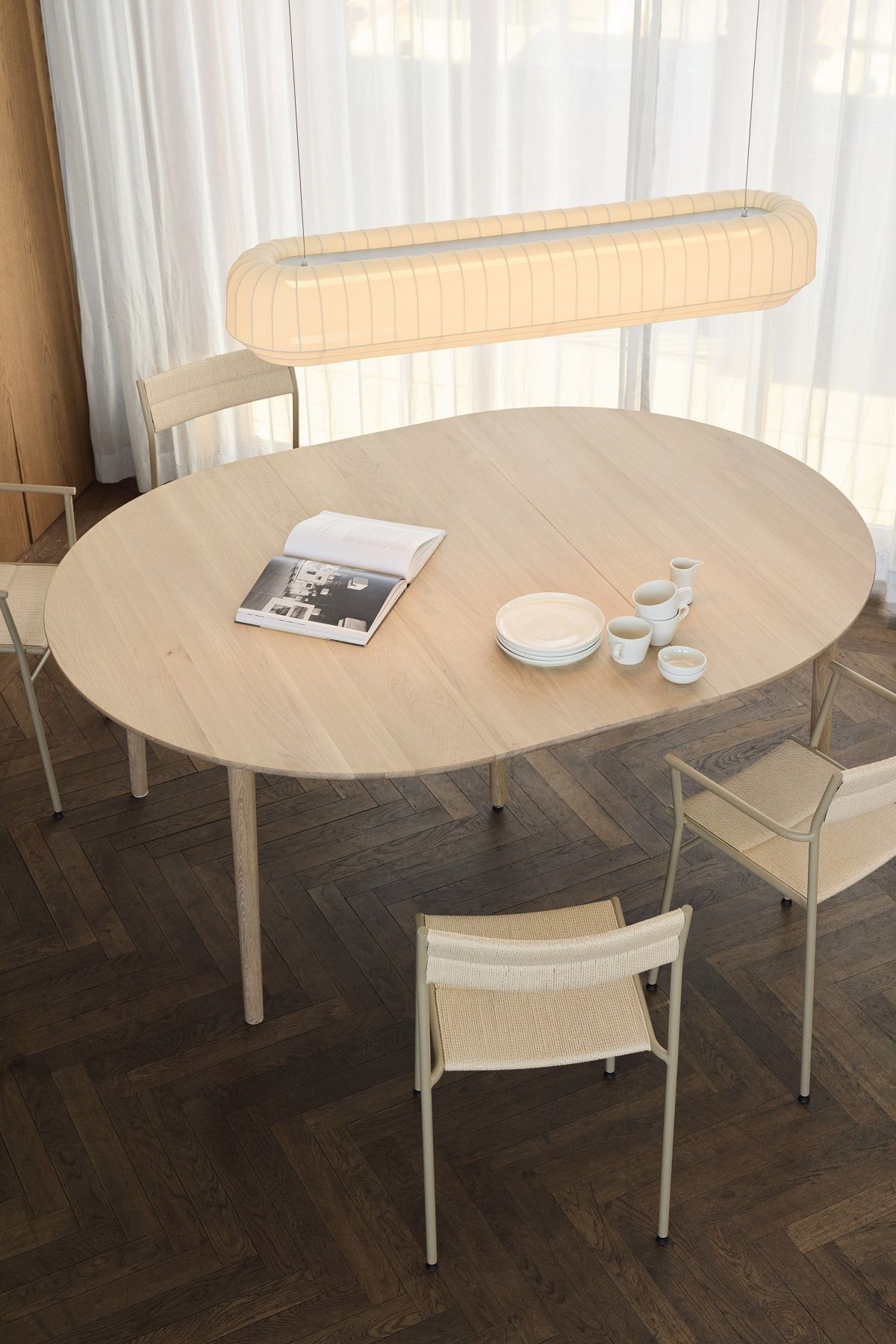 Northern Expand Esstisch aus hellem Holz, rund und ausgezogen, mit Stühlen und Geschirr in modernem Ambiente.