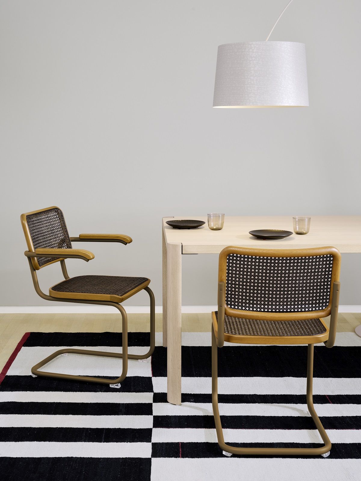 S 32 V Thonet Freischwinger Stühle aus Stahlrohr mit Armlehne und Wiener Geflecht am Esstisch.