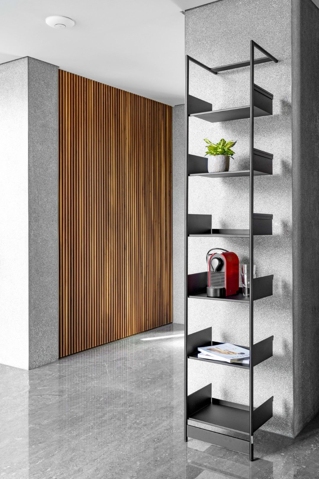 Schwarzes Pool 220 Anlehnregal von Mox an einer grauen Wand, dekoriert mit Pflanze, Kaffeemaschine und Magazin.
