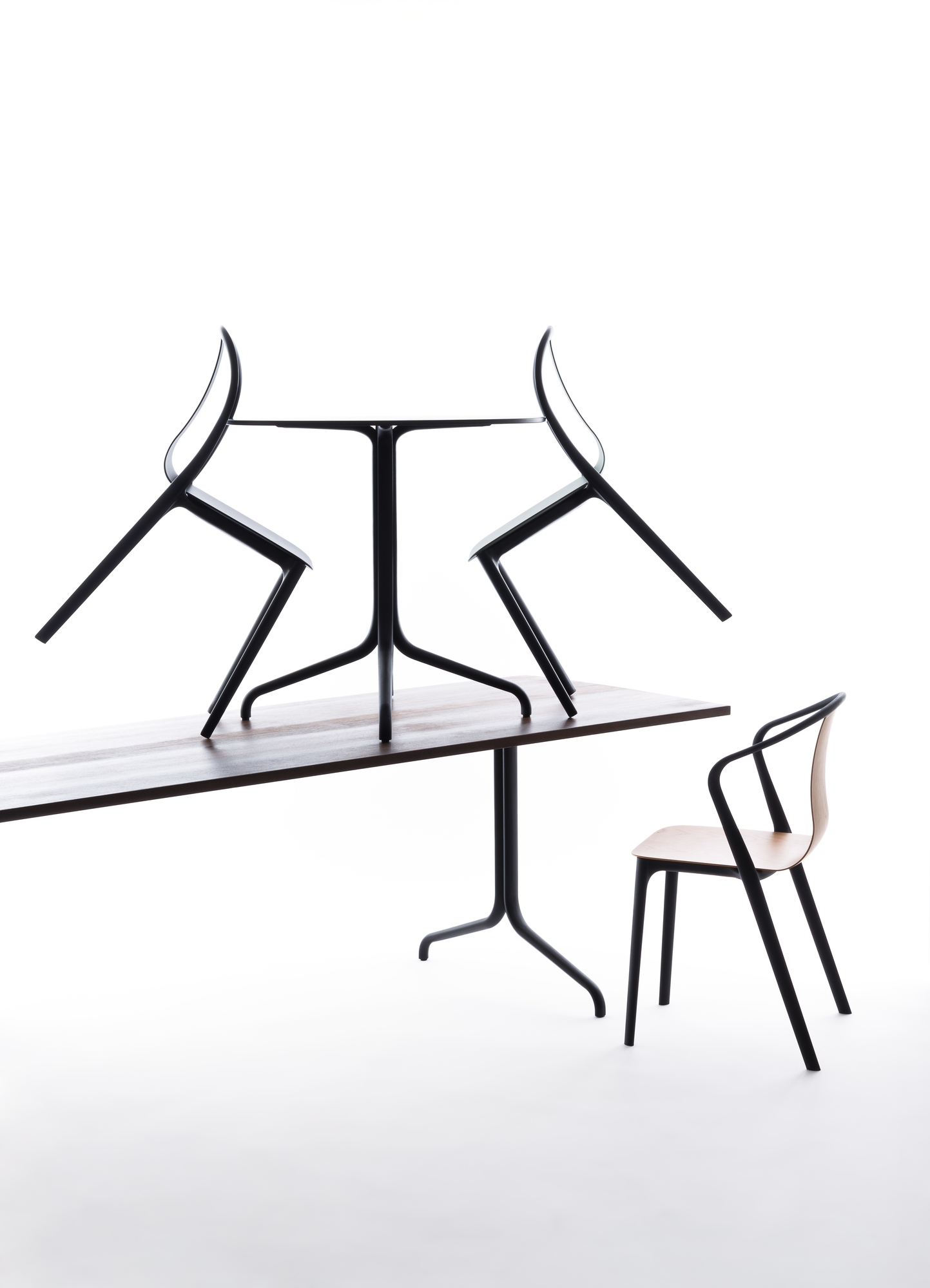 Vitra Belleville Chair Plastic Stuhl, schwarzes Gestell, Holz-Sitzfläche, zwei Stühle auf Tisch gestapelt.