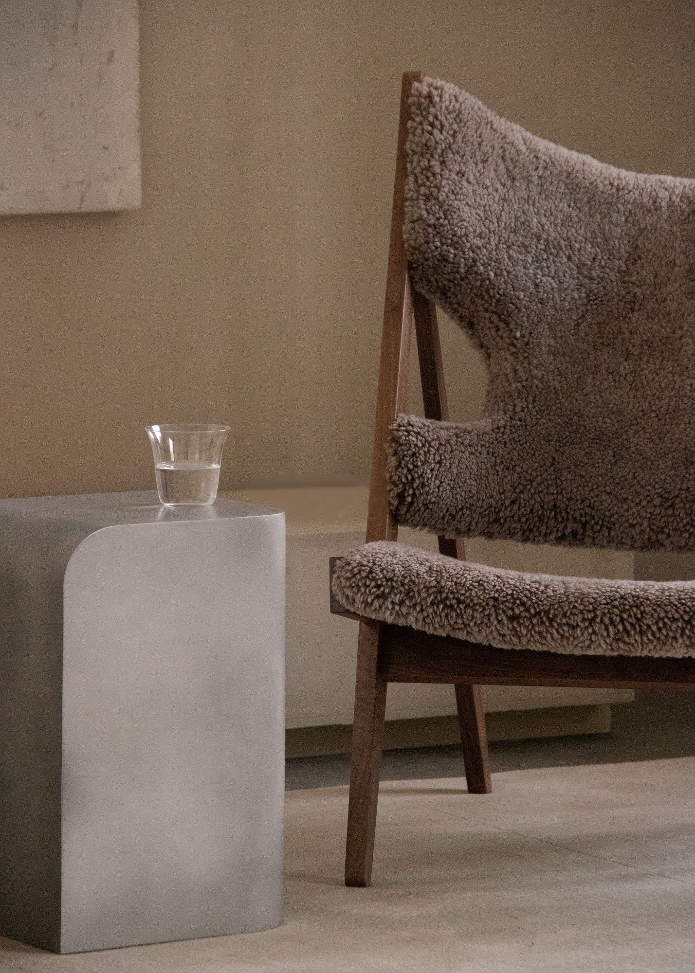 Audo Copenhagen Volume Side Table Beistelltisch aus Metall mit Wasserglas neben Sessel.
