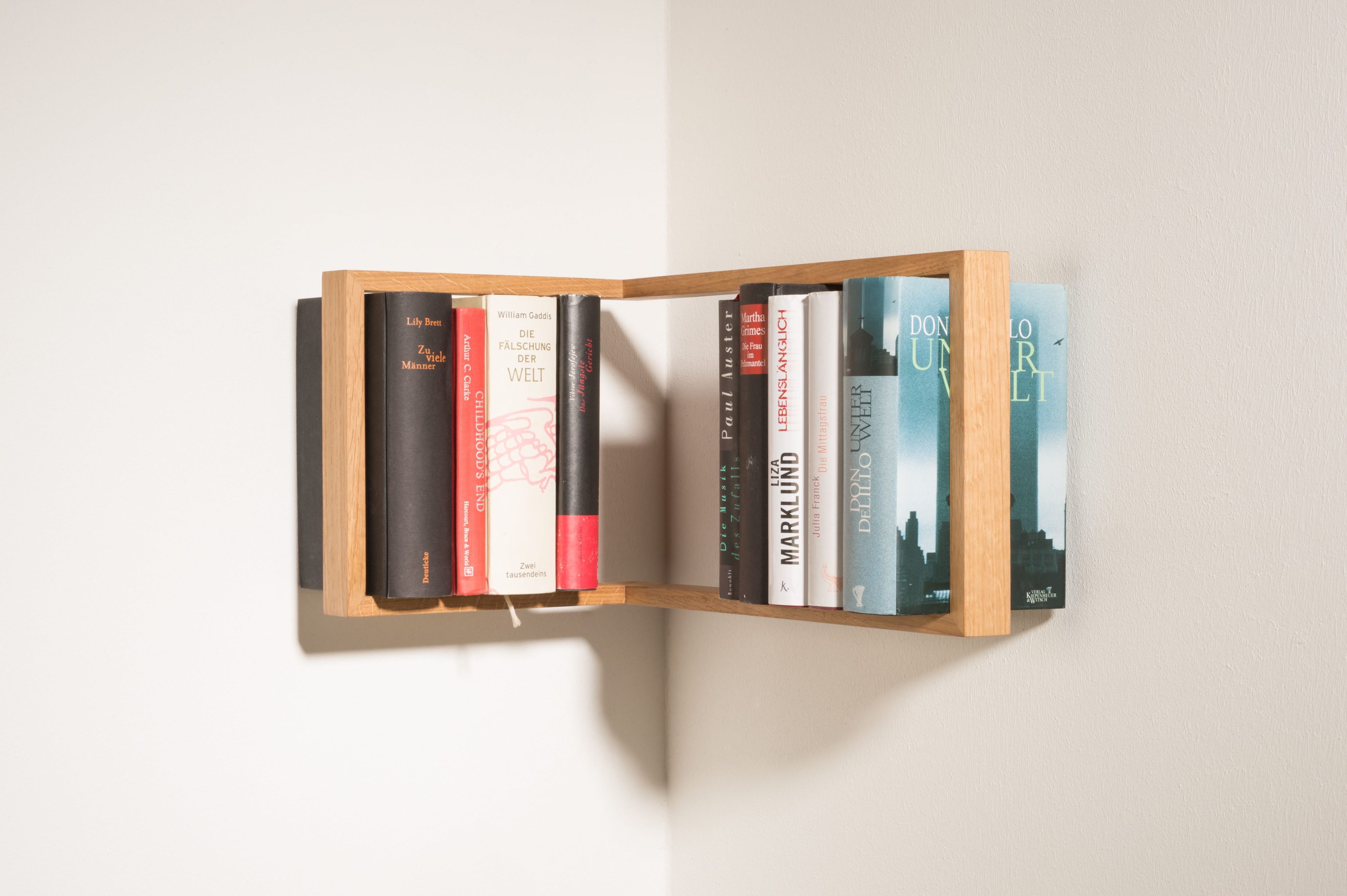 Regal b-eck Eiche, das kleine b: Eckregal aus Eichenholz mit Büchern an einer weißen Wand.