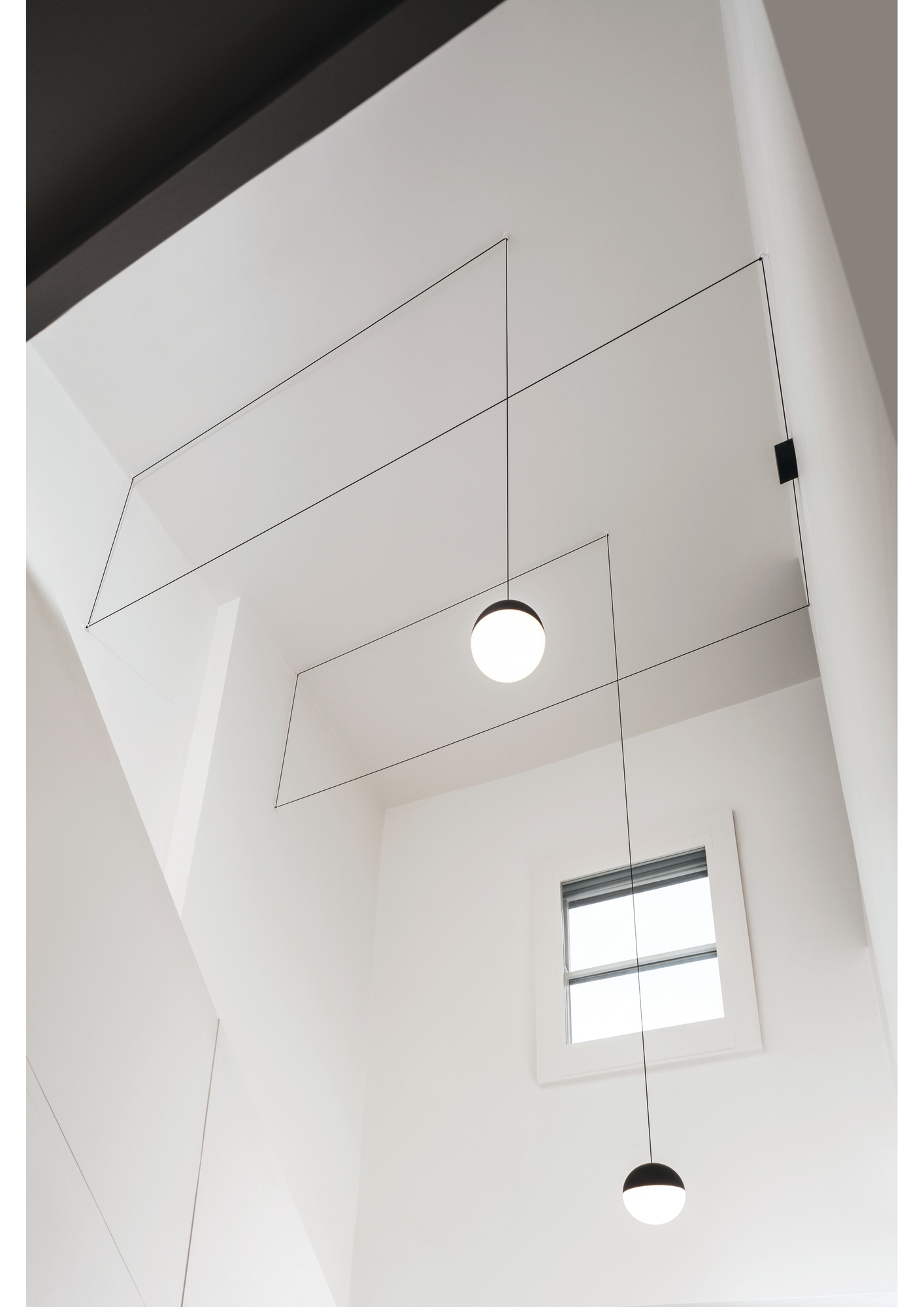 Flos String Light mit zwei Pendelleuchten und Wandrosette in modernem, weißem Interieur.