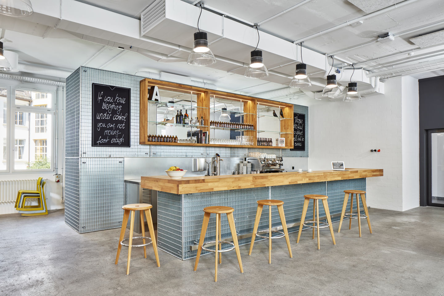 Innenaufnahme einer Bar mit Vitra Tabouret Haut Barhockern aus Holz und Chrom.