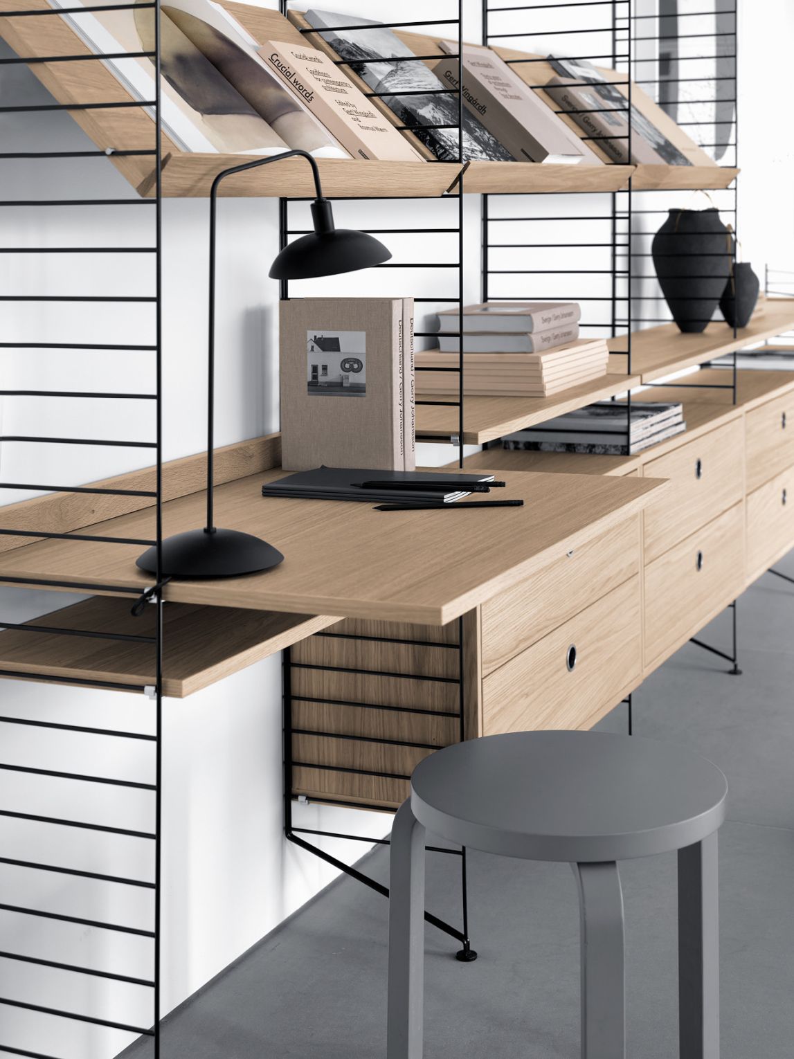 Detailaufnahme einer String Furniture Bodenleiter (H 85 cm) mit Regalen, Schreibtisch und Stauraumelementen.