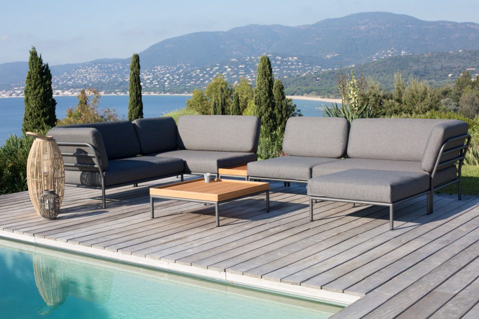 Graue Level Outdoor Lounge Ecke links von Houe mit Tisch auf Holzdeck am Pool.