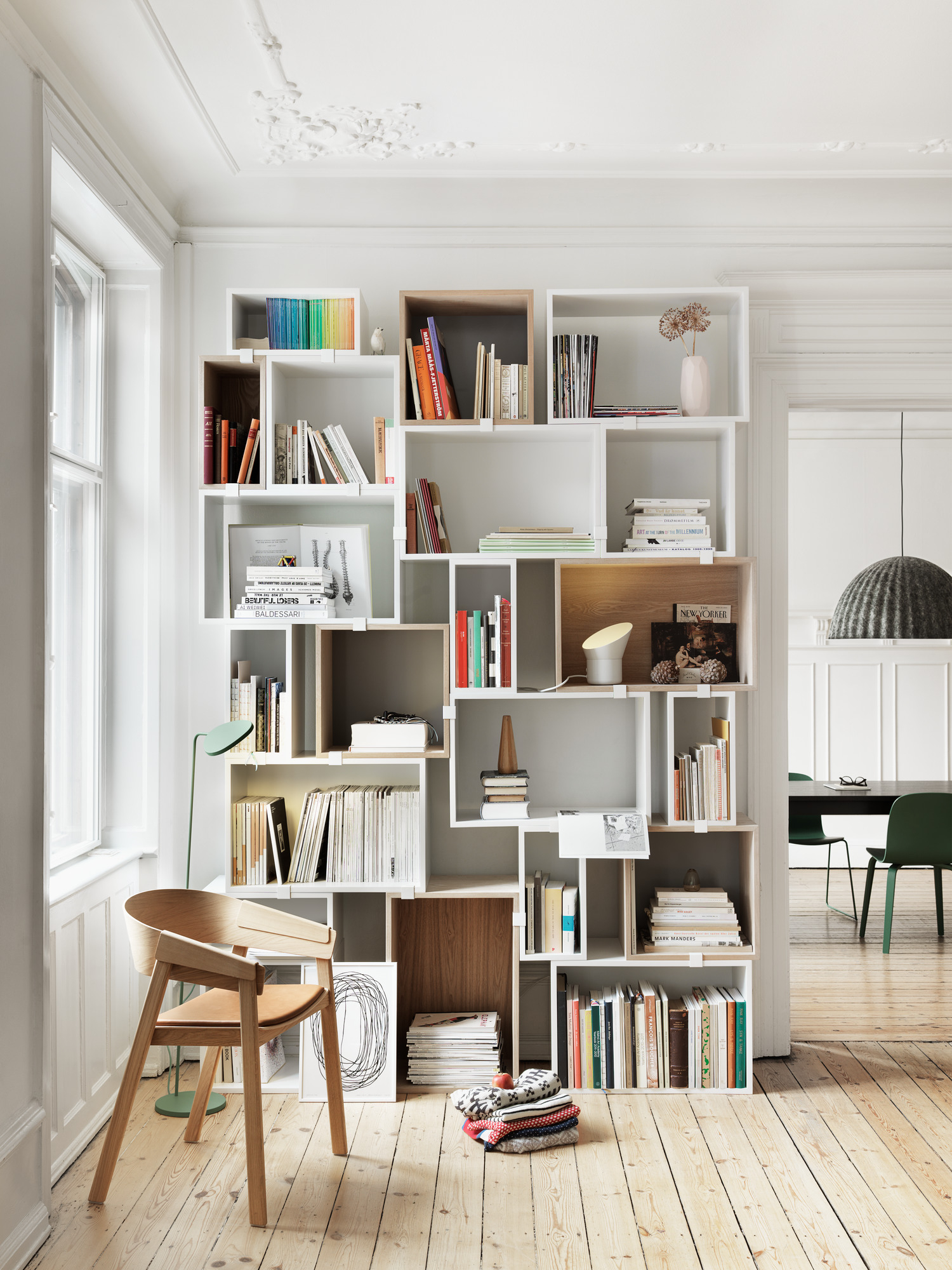 Muuto Visu Chair mit Holzgestell in heller Wohnung vor Bücherregal.