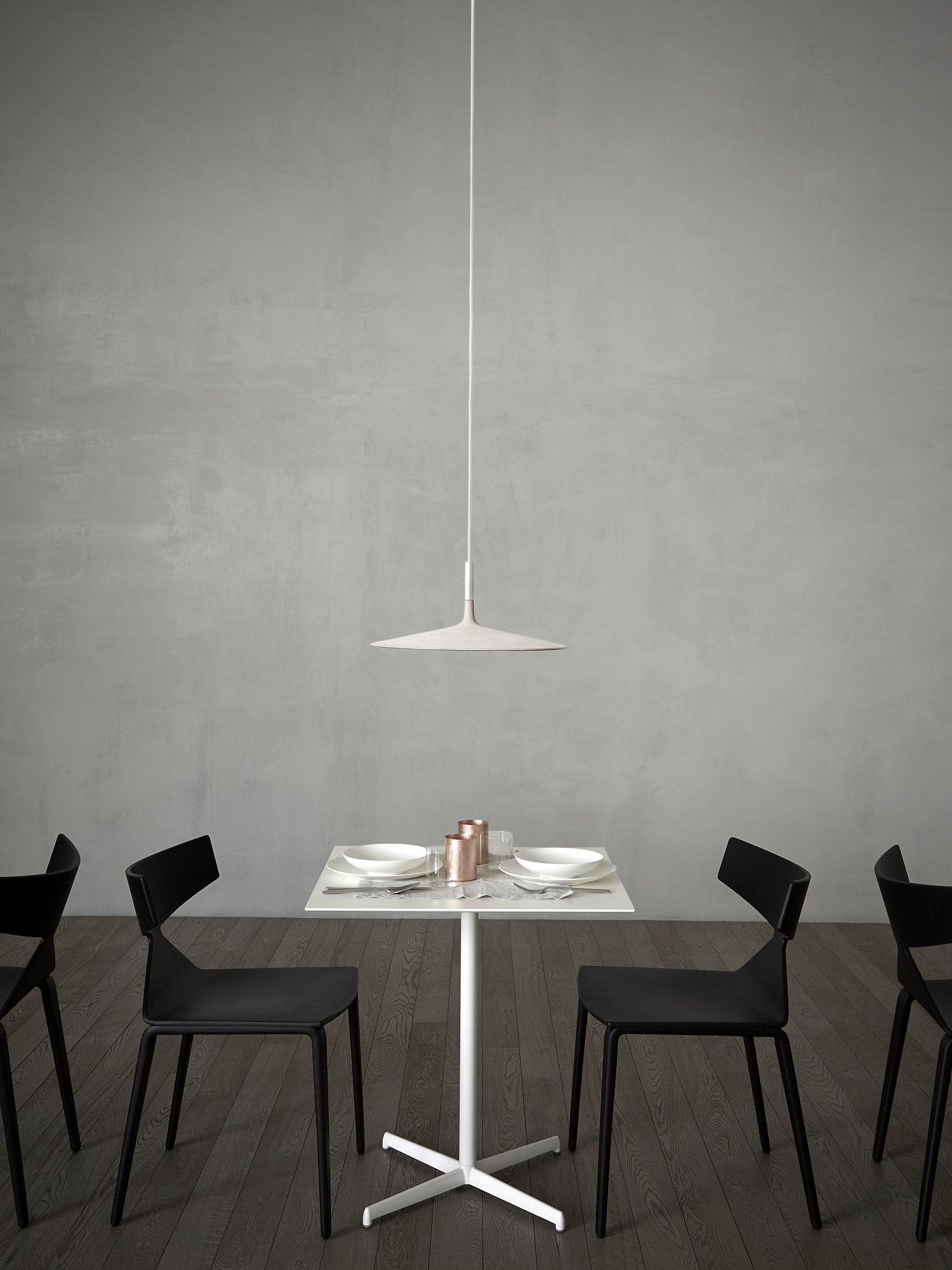Aplomb LED Pendelleuchte von Foscarini in Weiß über Esstisch mit schwarzem Stühlen.