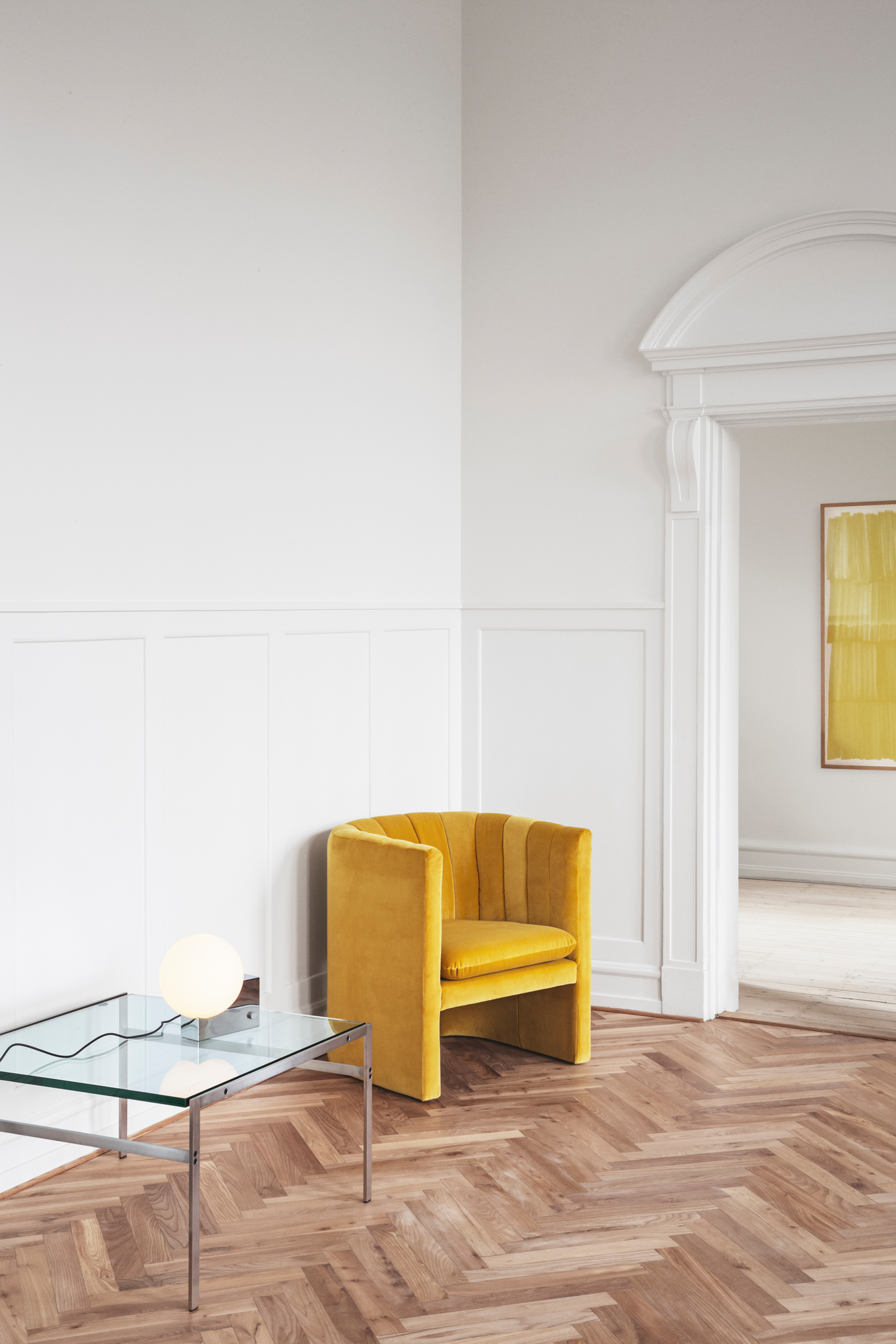 Gelber Loafer Sessel von AndTradition in modernem Interieur mit Glas-Couchtisch und Fischgrätenparkett.
