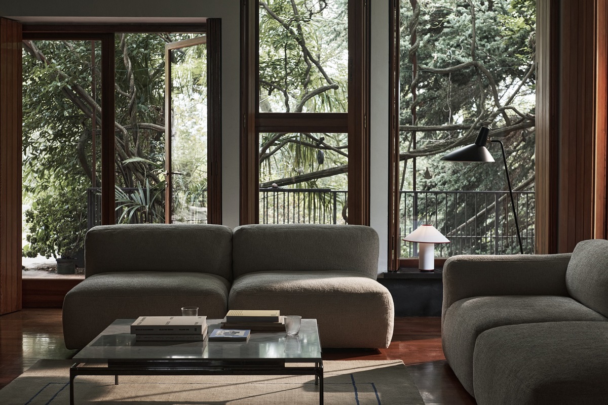 AndTradition Sett LN12 Couchtisch im Wohnzimmer mit modernem Sofa, Stehlampe und Blick ins Grüne.