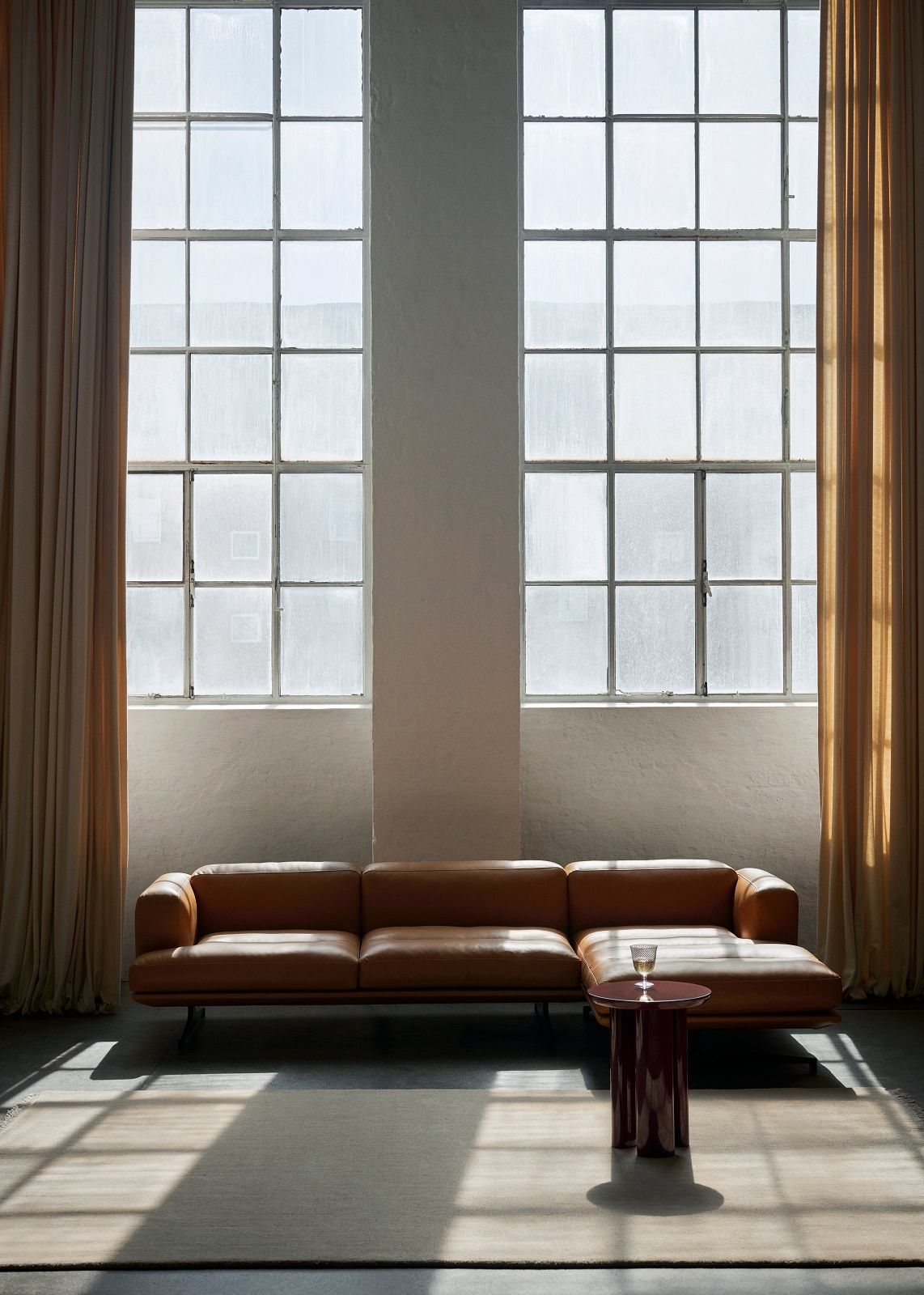 The Moor AP19 Rug Teppich von AndTradition in hellem Grau unter Ledersofa und Beistelltisch.