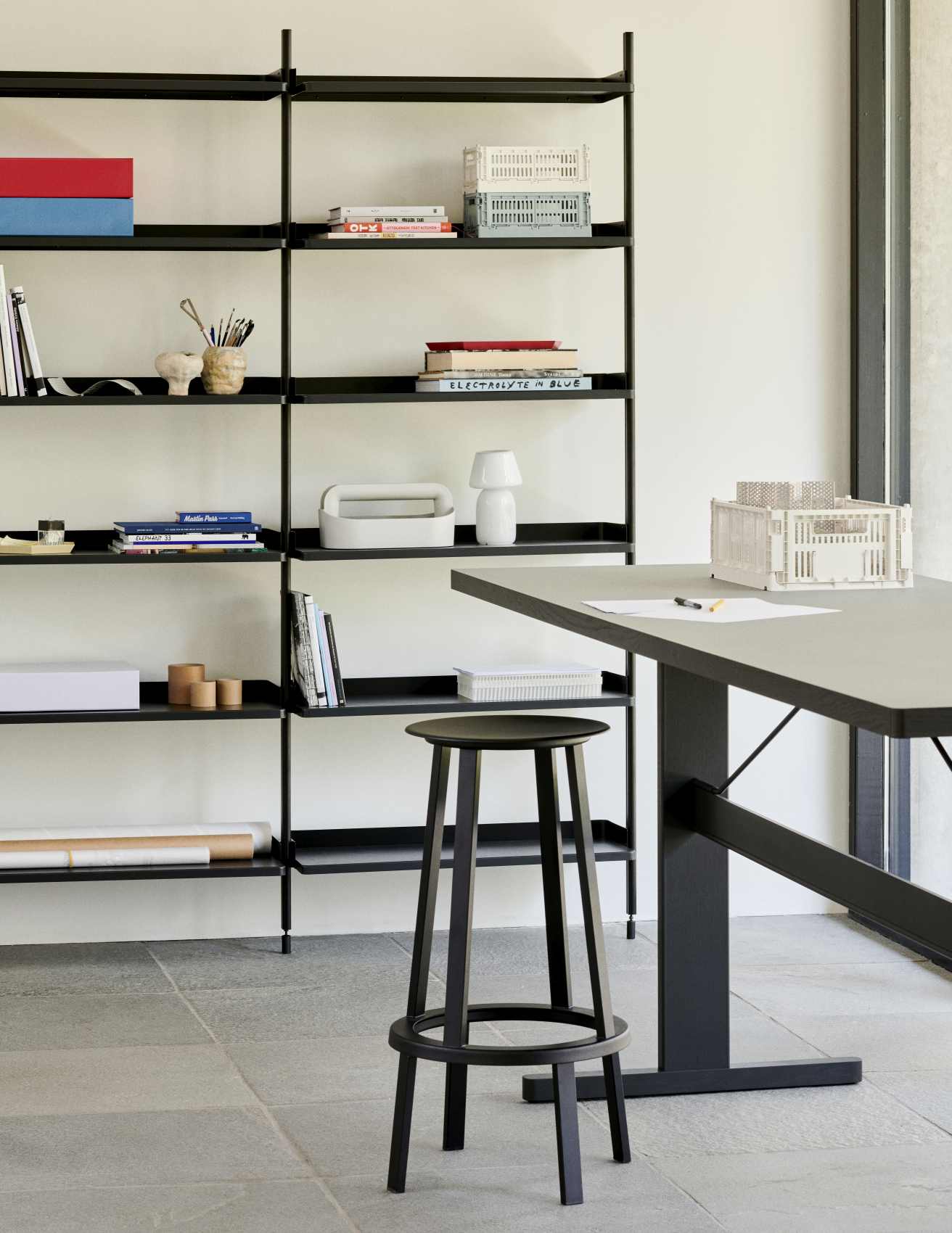 Schwarzer Revolver Bar Stool Barhocker von Hay vor Regal und Tisch in modernem Interieur.