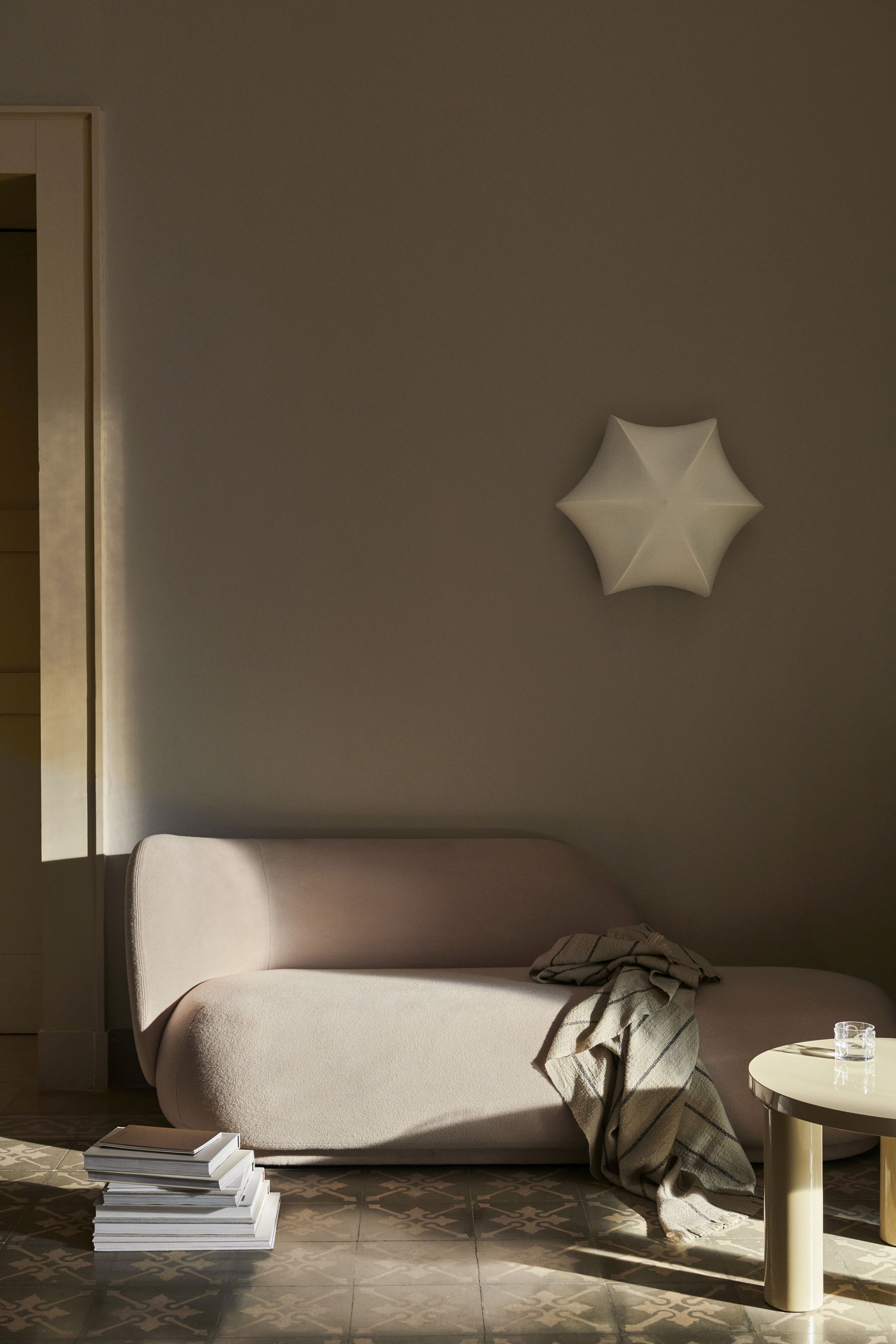 Beige Poem Wandleuchte von Ferm Living über Sofa im Wohnzimmer mit Tageslicht.