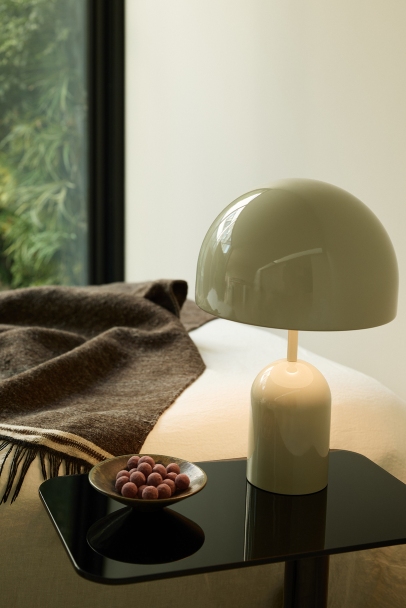 Bell Portable LED Tischleuchte von Tom Dixon in Kupfer auf einem Nachttisch.