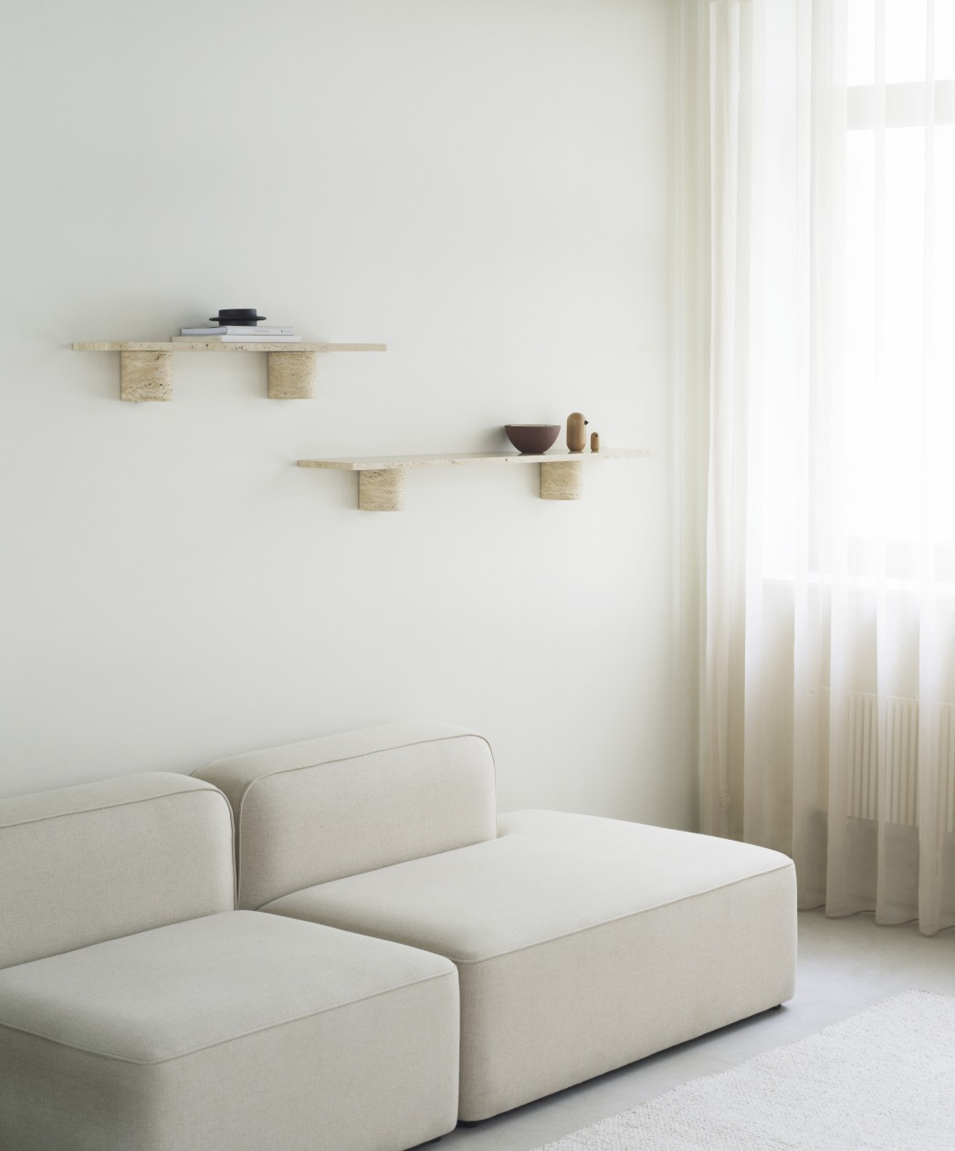 Zwei helle Sten Regale von Normann Copenhagen an einer Wand über einem Sofa.
