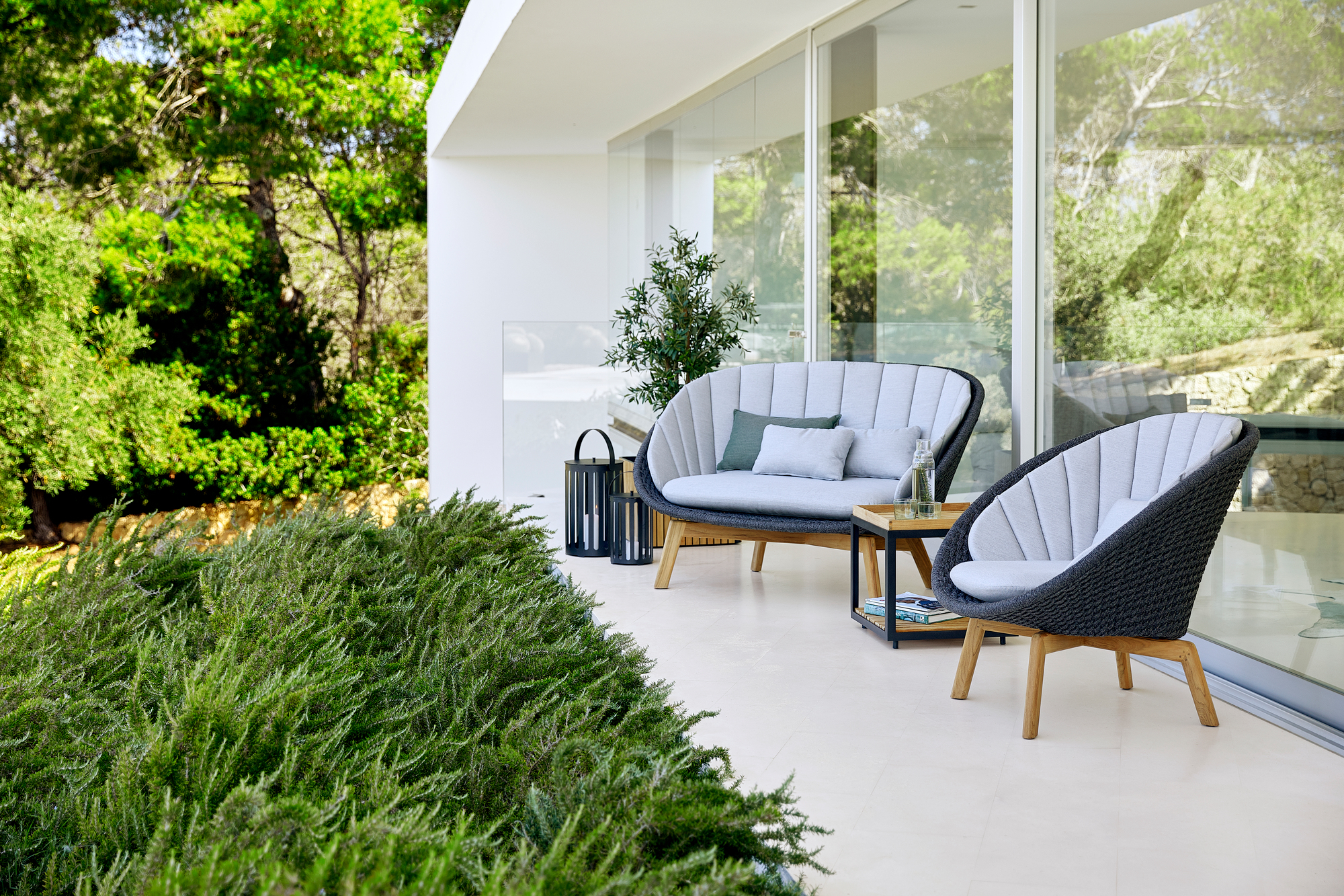 Peacock Outdoor Sofa von Cane-Line auf einer Terrasse mit Gartenmöbeln und stilvollem Design.