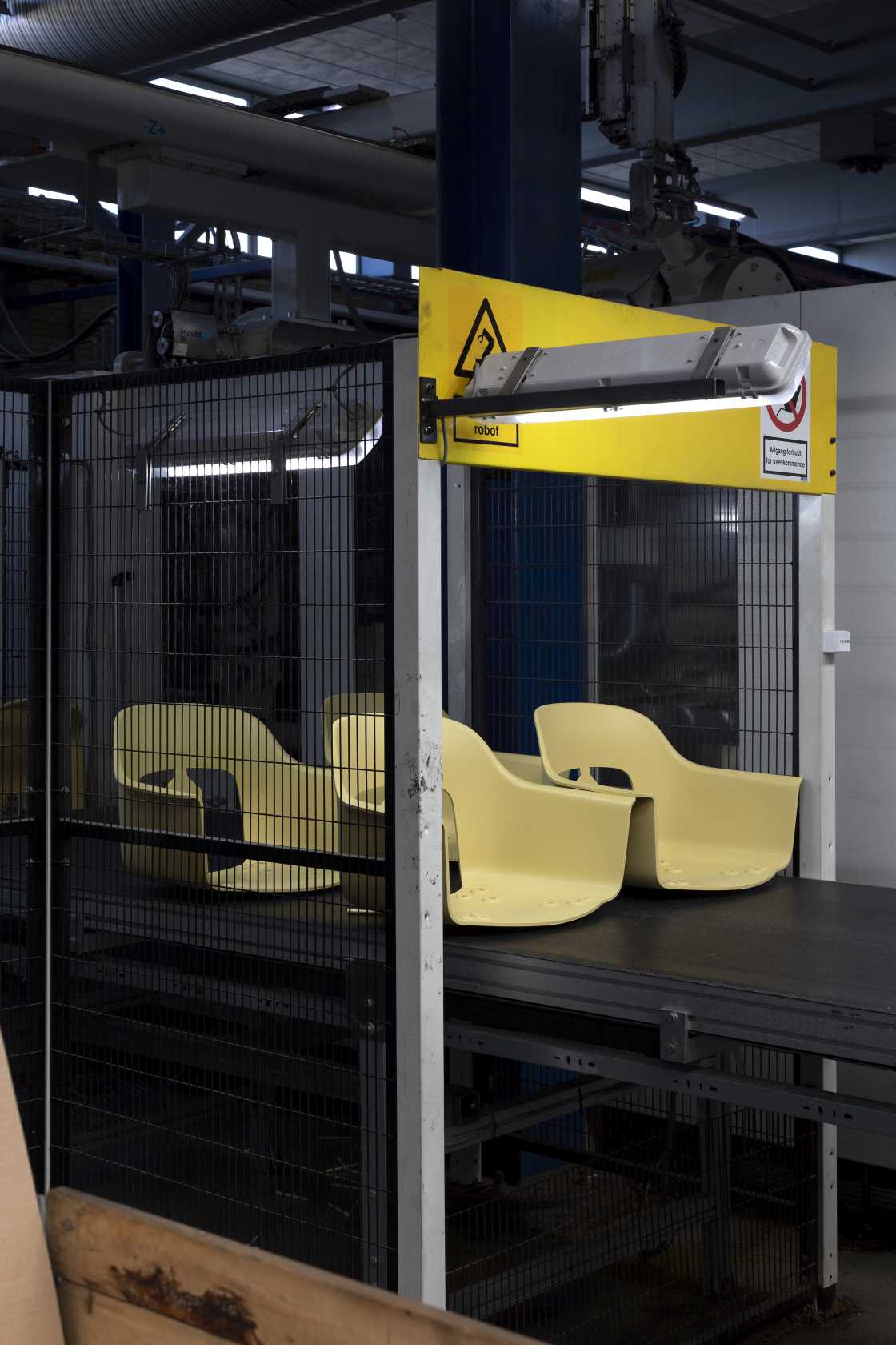 Gelbe Hay Layout Armchair 212 Armlehnstuhl-Sitzschalen auf einem Förderband in einer Produktionsanlage, Fokus auf nachhaltige Möbelherstellung.