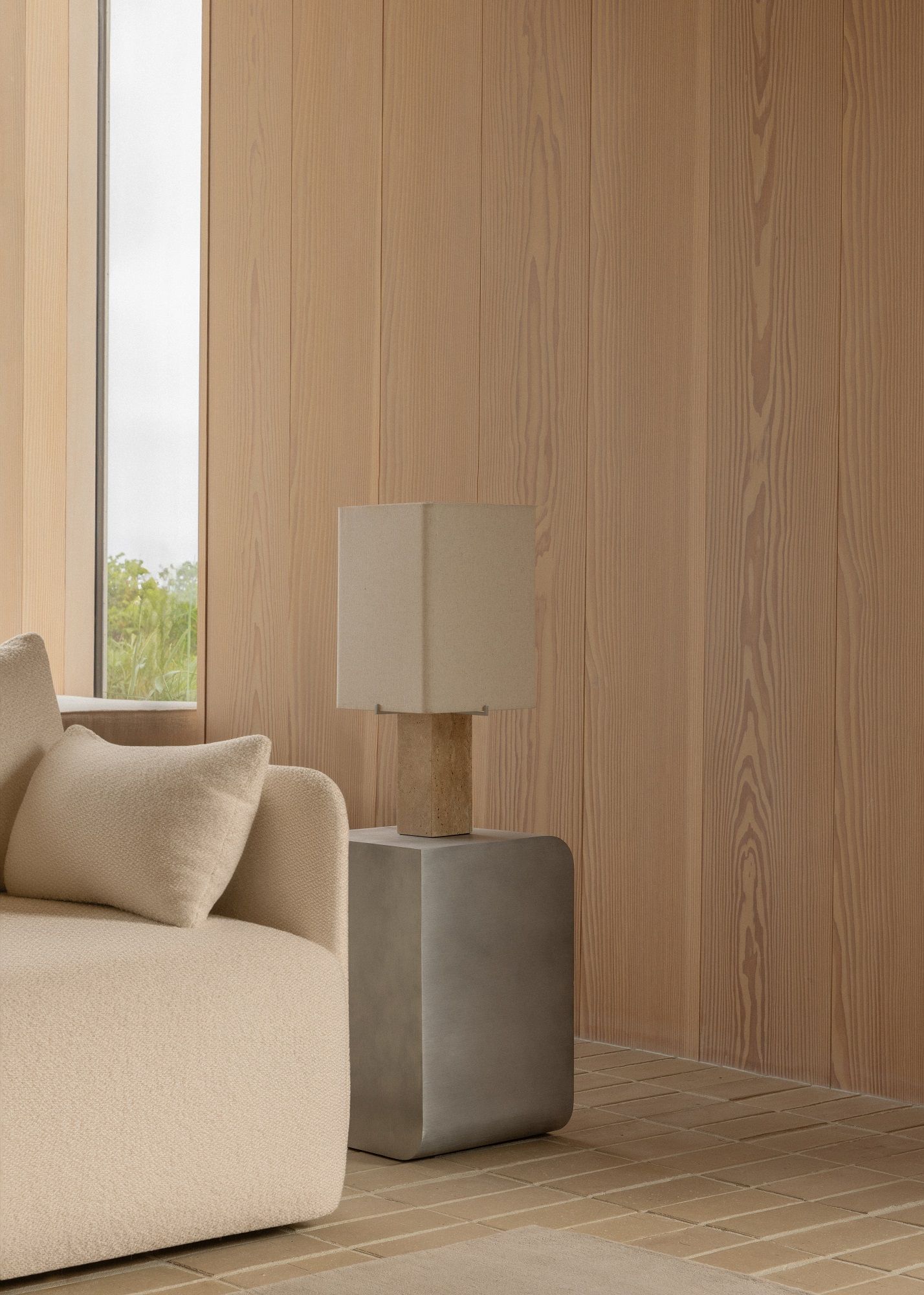 Audo Copenhagen Volume Side Table Beistelltisch aus grauem Beton neben einem beigen Sofa mit Kissen.