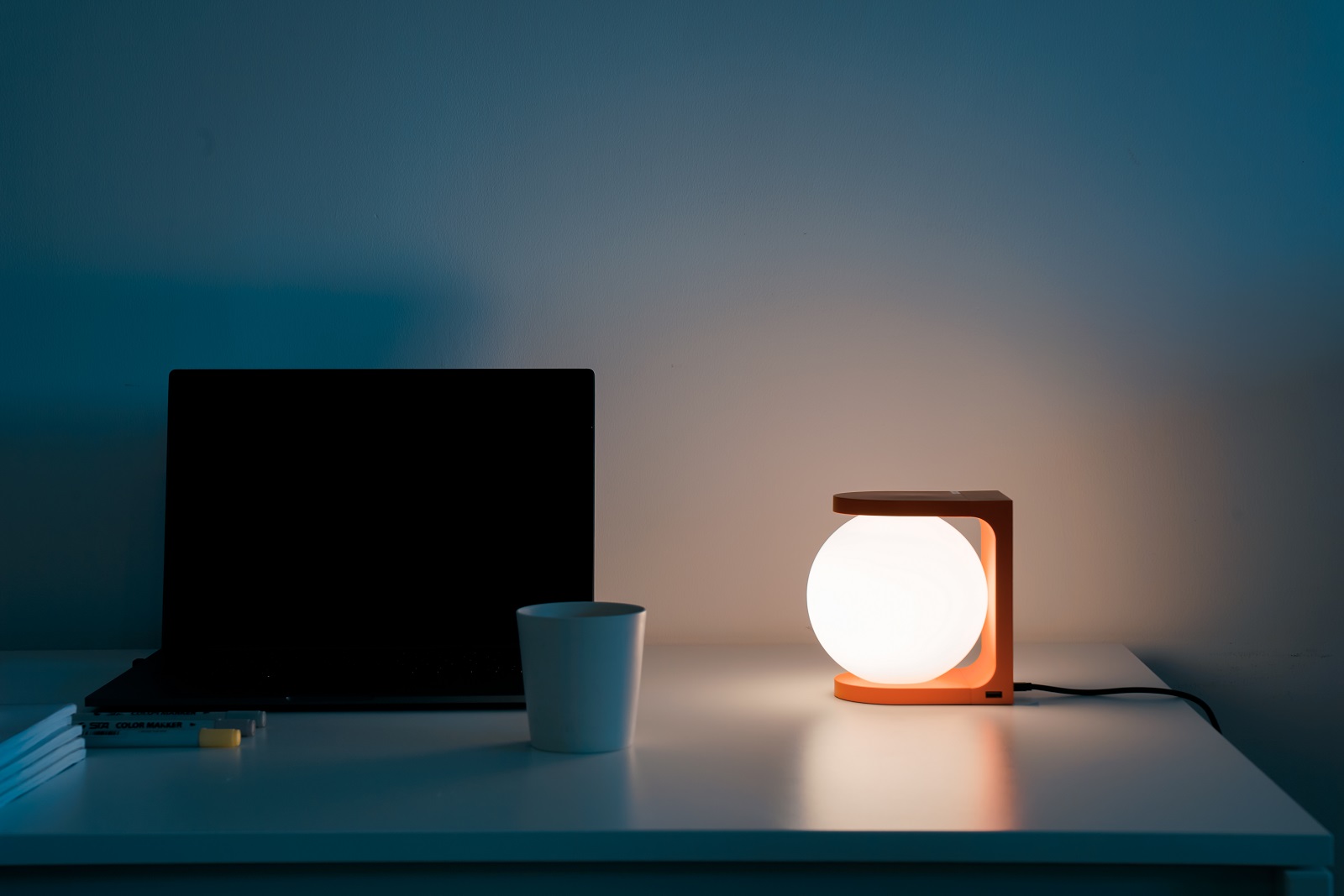 Nahaufnahme der orangefarbenen Plat Reading Lamp Tischleuchte von house of home auf einem Schreibtisch.