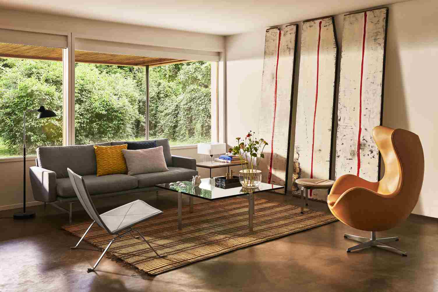 Helles Wohnzimmer mit grauem Lissoni Sofa von Fritz Hansen, Sessel, Teppich und Kunst.