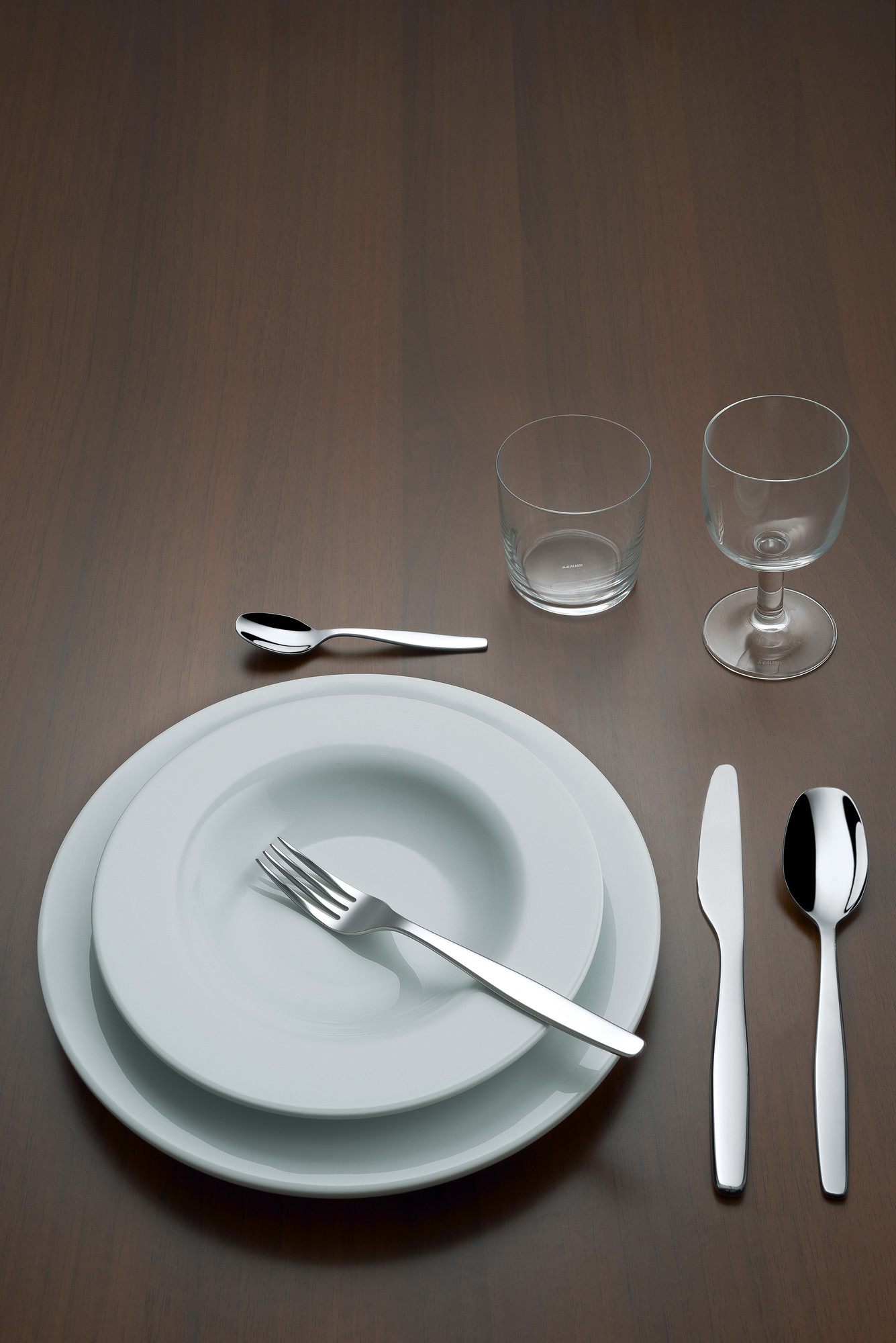 ANF06S24 Alessi Besteckset: Teller, Besteck und Gläser auf einem Holztisch. Hochwertiges Essbesteck.
