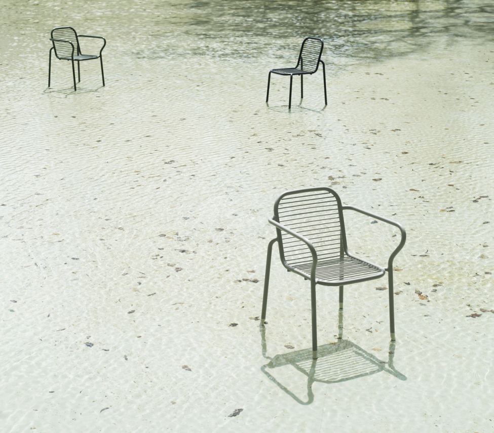 Drei graue Vig Chair Stühle von Normann Copenhagen stehen im flachen Wasser, Outdoor Möbel.