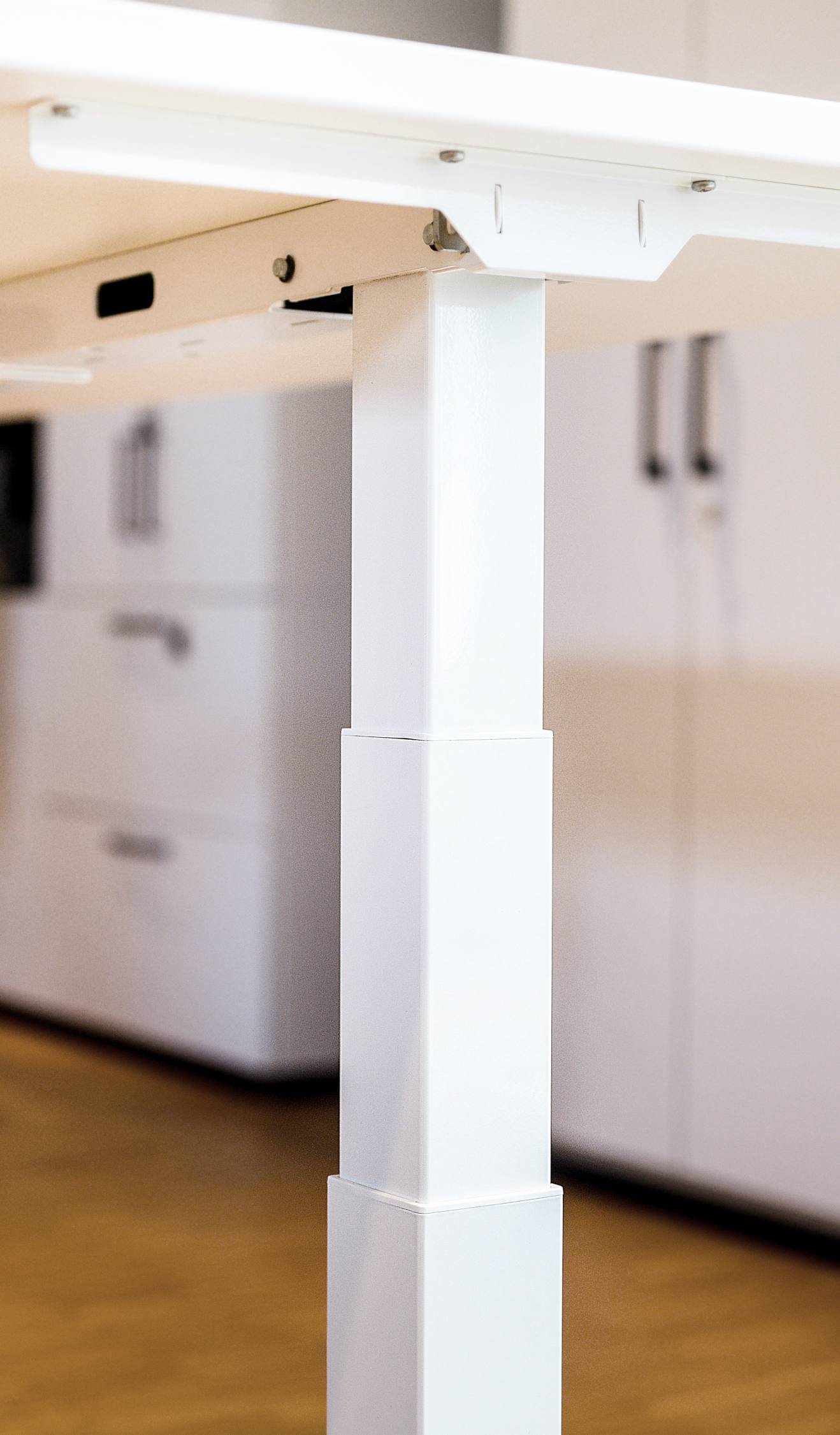 Detailaufnahme des weißen, elektrisch höhenverstellbaren Hiplift Sitz-Stehtischs für ergonomisches Arbeiten im Büro.