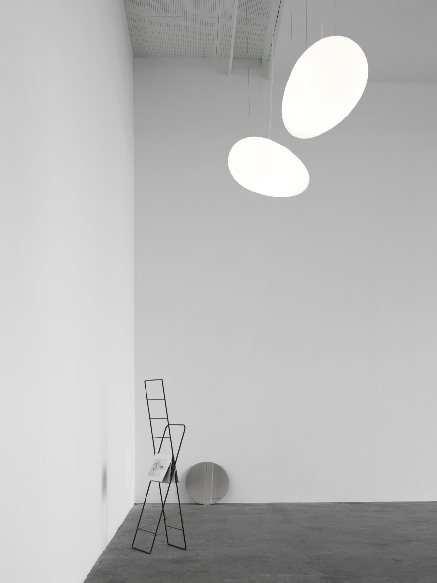 Zwei moderne Avion Pendelleuchten von Fritz Hansen in einem minimalistischen Raum mit Magazinhalter.