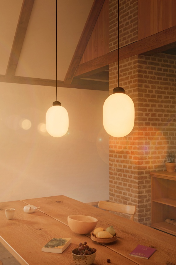 Zwei graue Sun Pendelleuchten über Esstisch. Moderne Hängelampe für stilvolle Beleuchtung im Esszimmer.