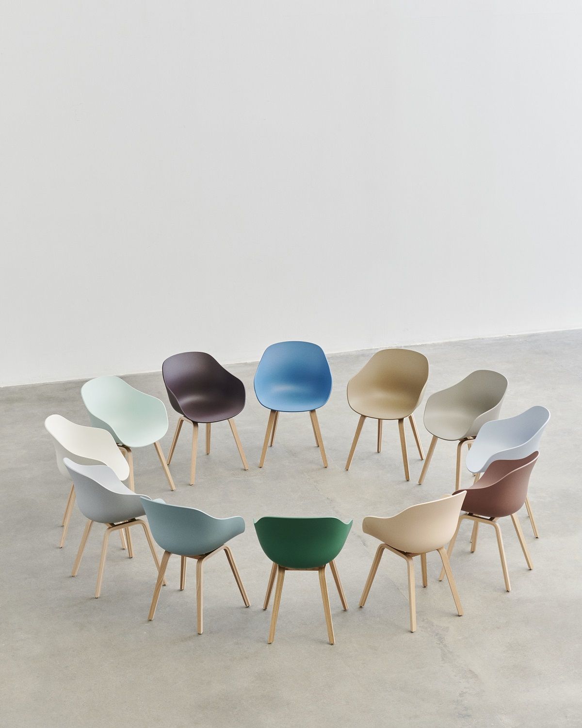 Kreisförmige Anordnung von zwölf Hay About a Chair AAC 222 Stühlen in verschiedenen Farben.
