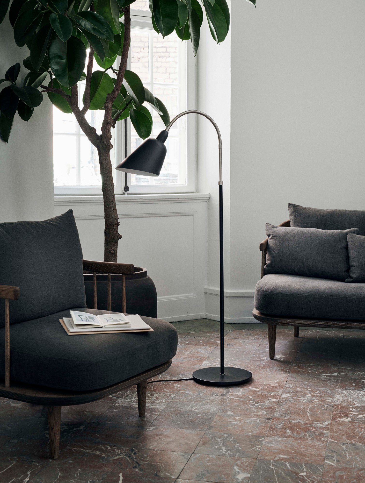 Fly Lounge Sessel von AndTradition: Grauer Sessel mit Holzelementen und passendem Sofa im Wohnzimmer.