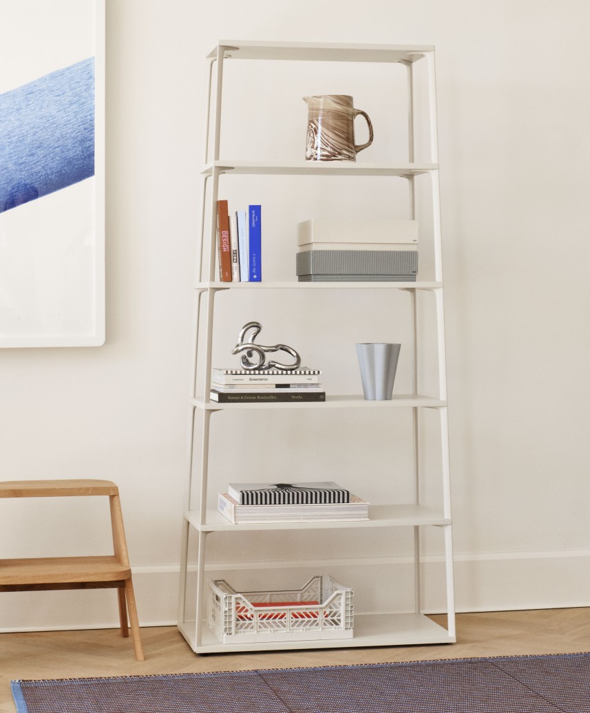 Weißes Regal "Butler" von Hay mit fünf Ablageflächen, dekoriert mit Büchern und Wohnaccessoires.