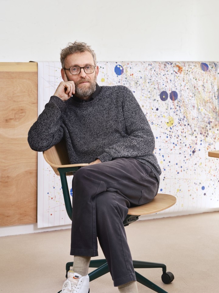 Mann sitzt auf einem Mynt Bürodrehstuhl von Vitra mit Rückenlehne aus Kunststoff und grünem Gestell.