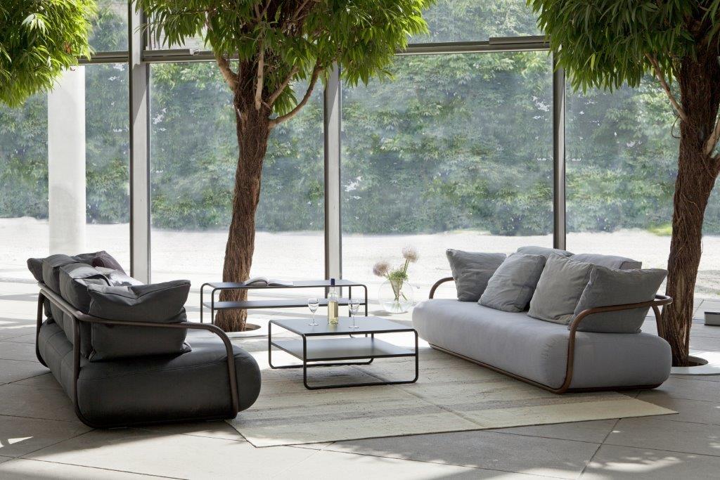 Helles Interieur mit grauem Thonet 2002 Bugholz-Sofa, schwarzem Ledersofa, Couchtisch und Blick durch große Fenster.