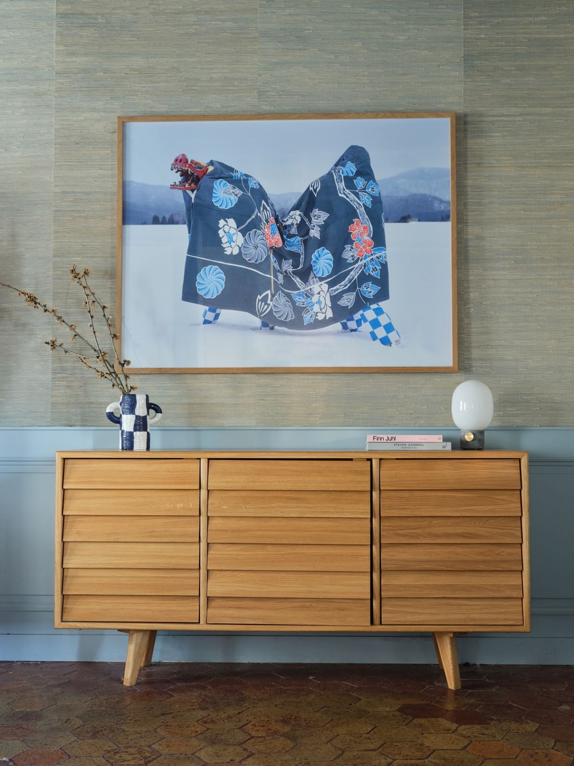 Heller Holzschrank mit Schubladen und Foto eines japanischen Drachenkostüms als Wanddekoration.