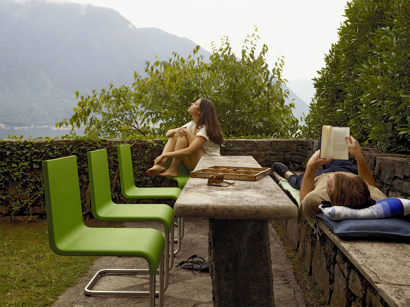Drei grüne Vitra .05 Stühle im Garten, eine Frau sitzt entspannt auf einem Stuhl.