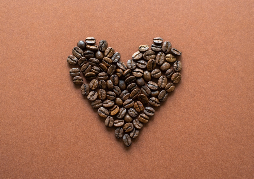 Herz aus gerösteten Kaffeebohnen auf braunem Hintergrund. Premium Kaffee für Kaffeeliebhaber.