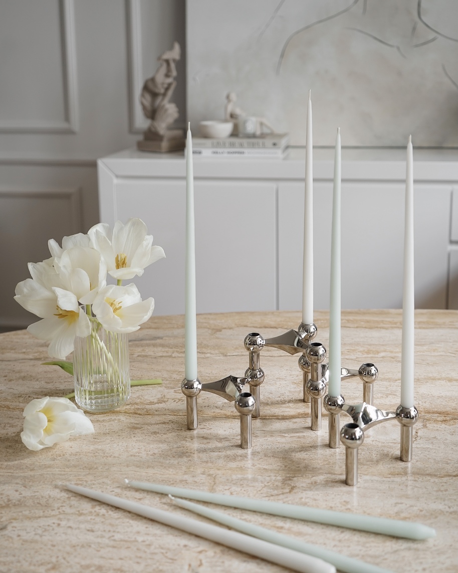 Produktfoto: Weißes Kerzen 6er Set im Stoff Nagel Kerzenständer mit Tulpen auf einem Tisch.