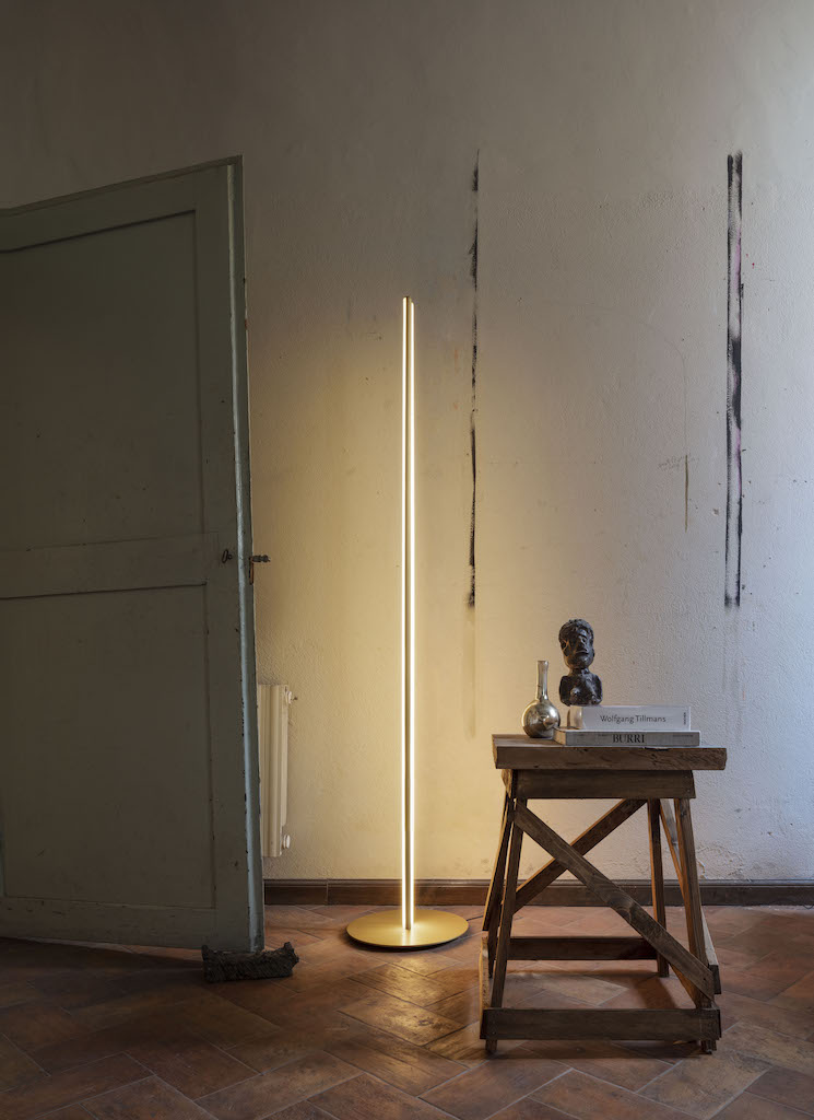 Coordinates F LED Stehleuchte von Flos: Moderne, vertikale LED-Stehlampe mit warmem Licht und goldener Basis.