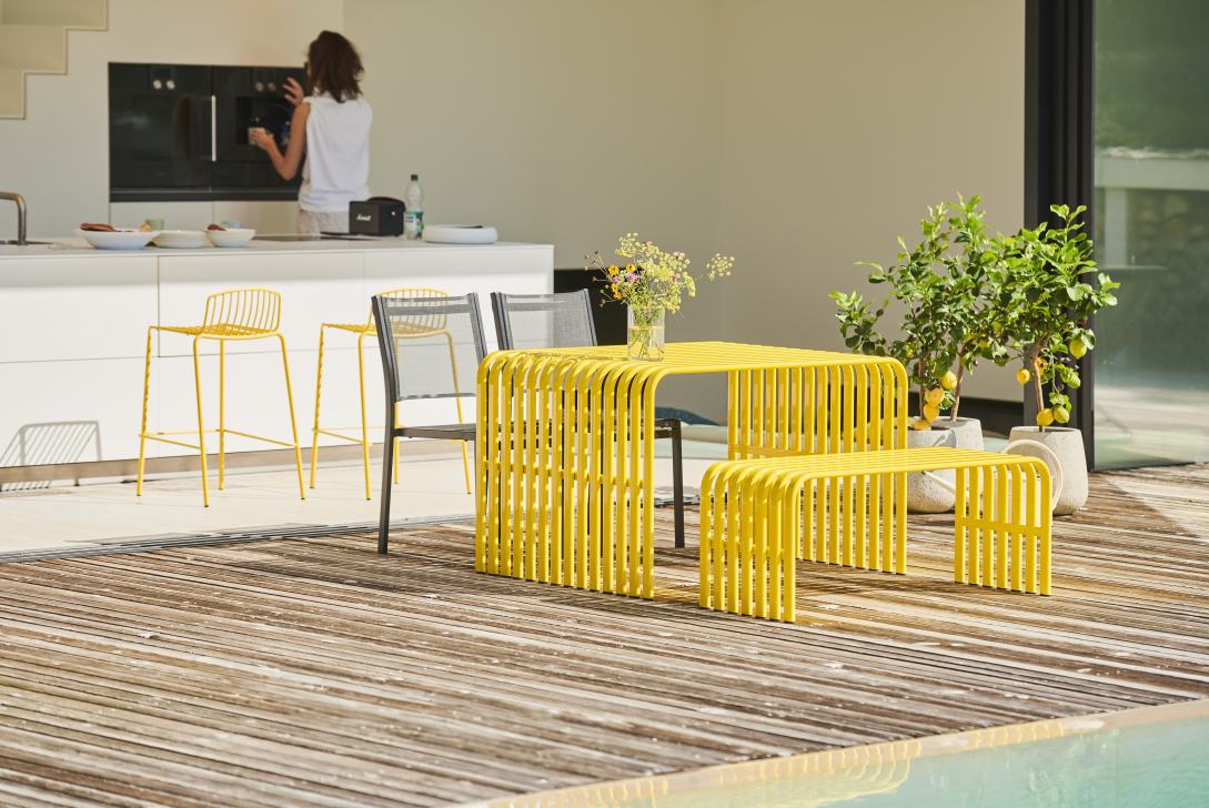 Gelbe Campus Bank von Jan Kurtz für den Außenbereich mit Tisch und Sitzbank auf Holzterrasse.
