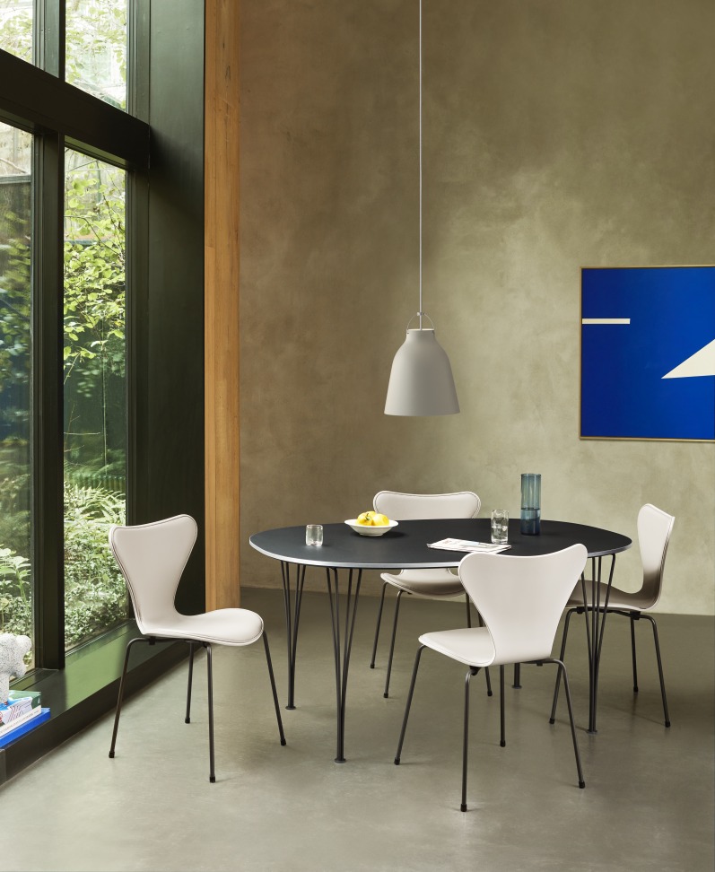 Graue Caravaggio Pendelleuchte von Fritz Hansen über Esstisch mit Stühlen in modernem Interieur.