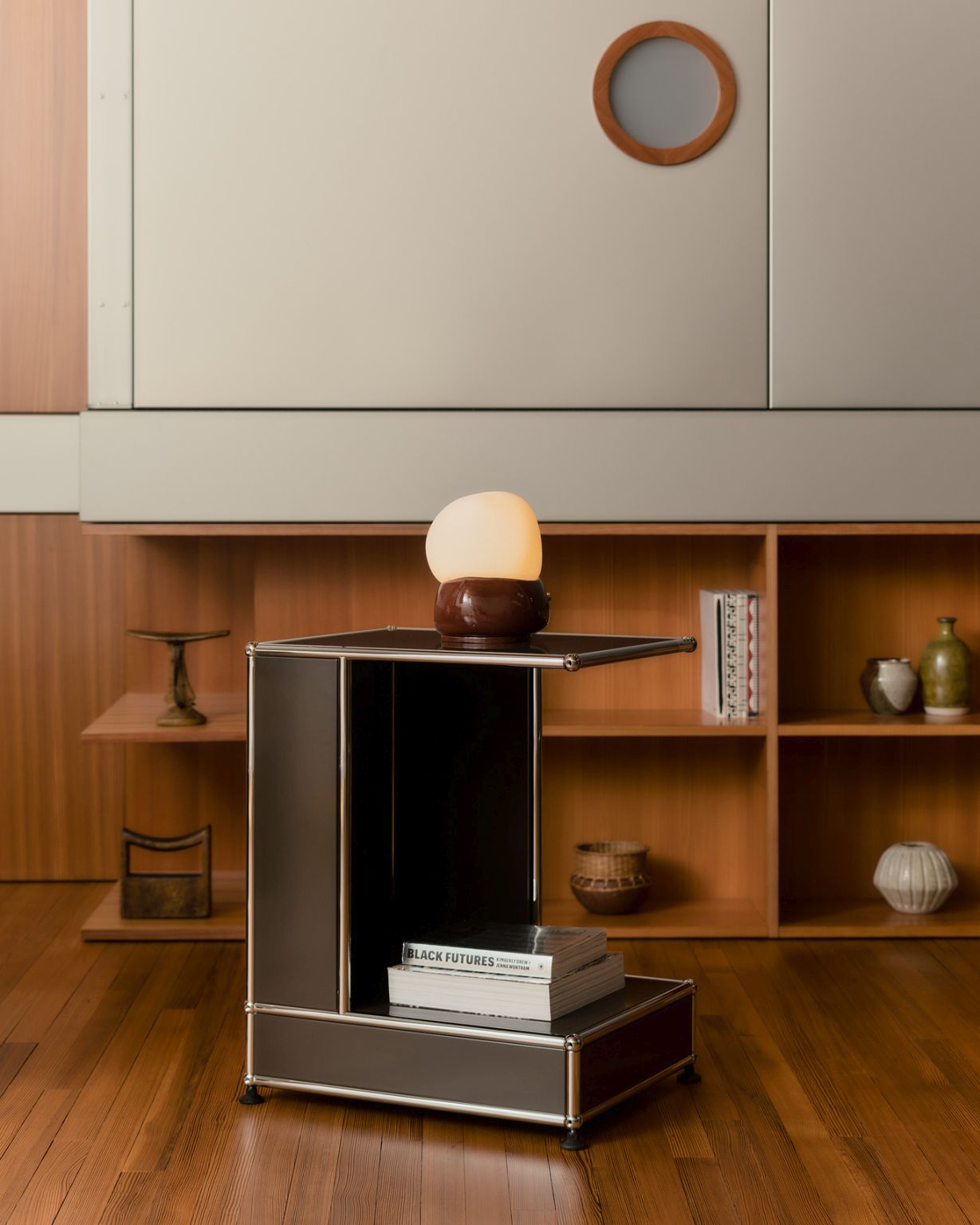 USM Haller Beistelltisch Arkad von Armando Cabral in Braun mit Lampe und Büchern im Wohnzimmer.