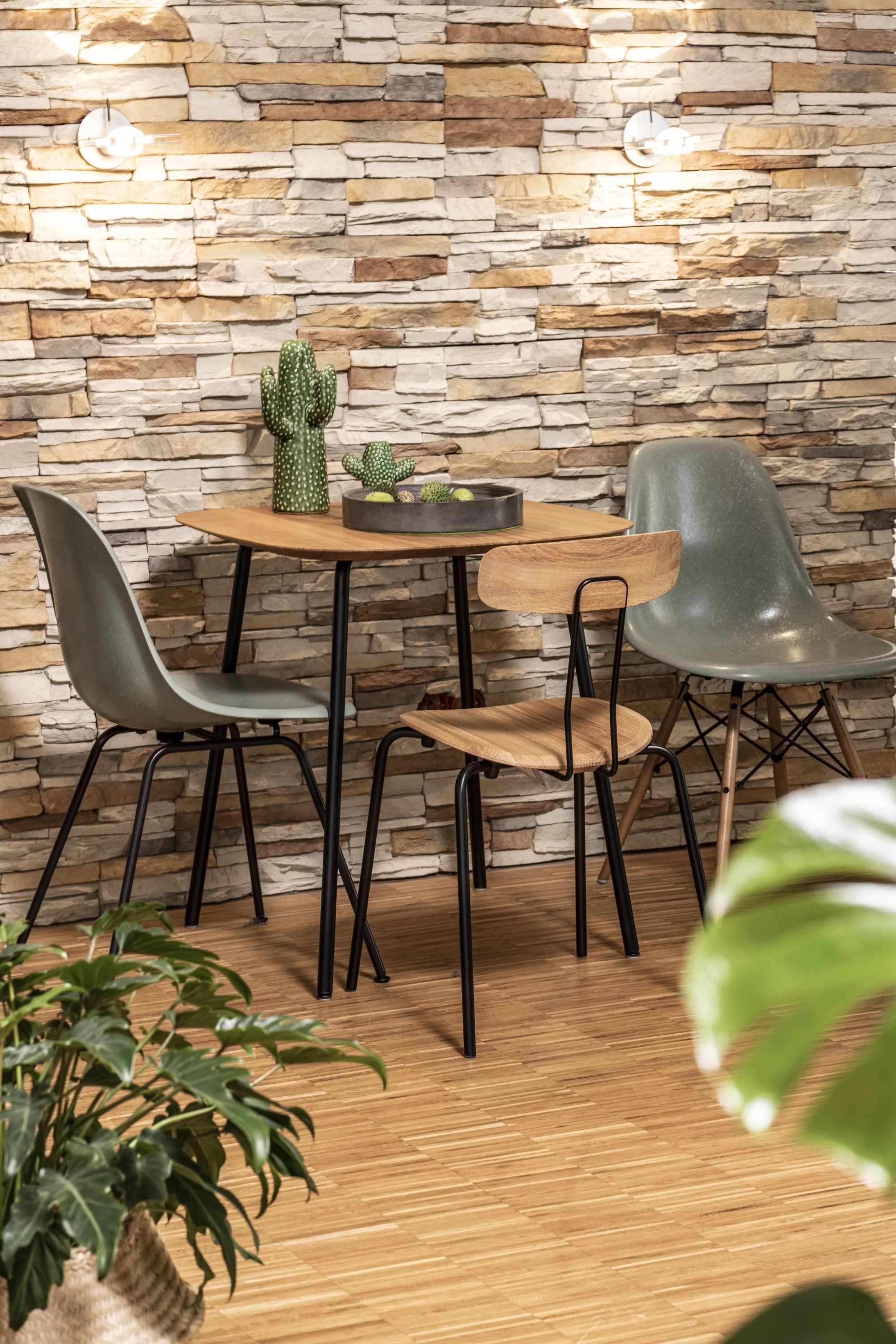 Esstisch mit Holzplatte und drei Stühlen in modernem Design vor Steinwand.