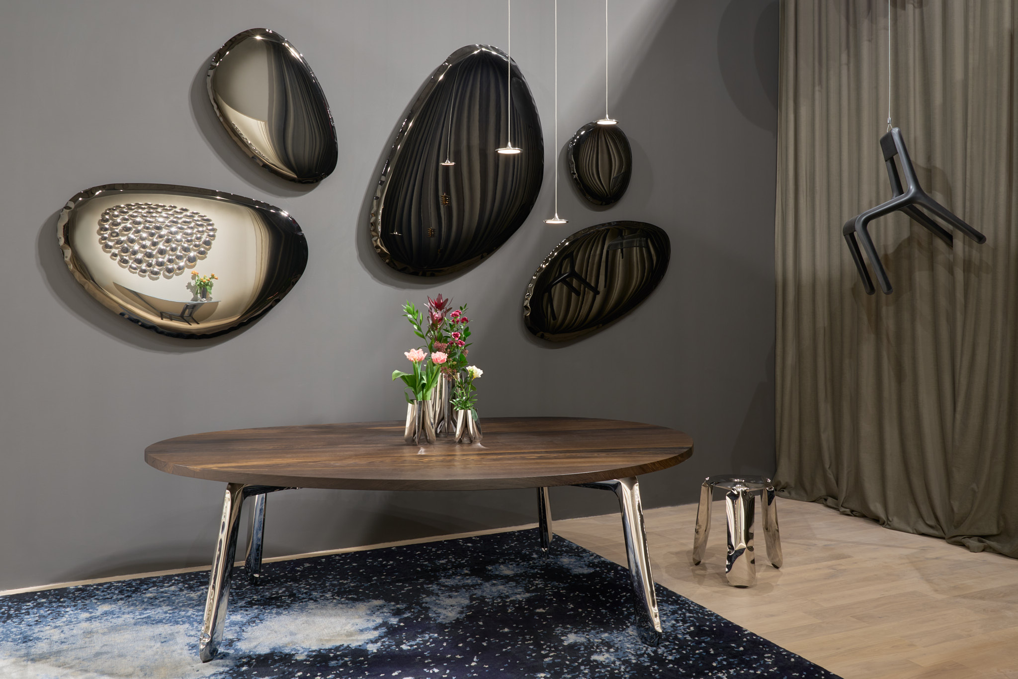 Tafla Spiegel "Dark Matter" von Zieta mit organischen Formen an grauer Wand über Esstisch.