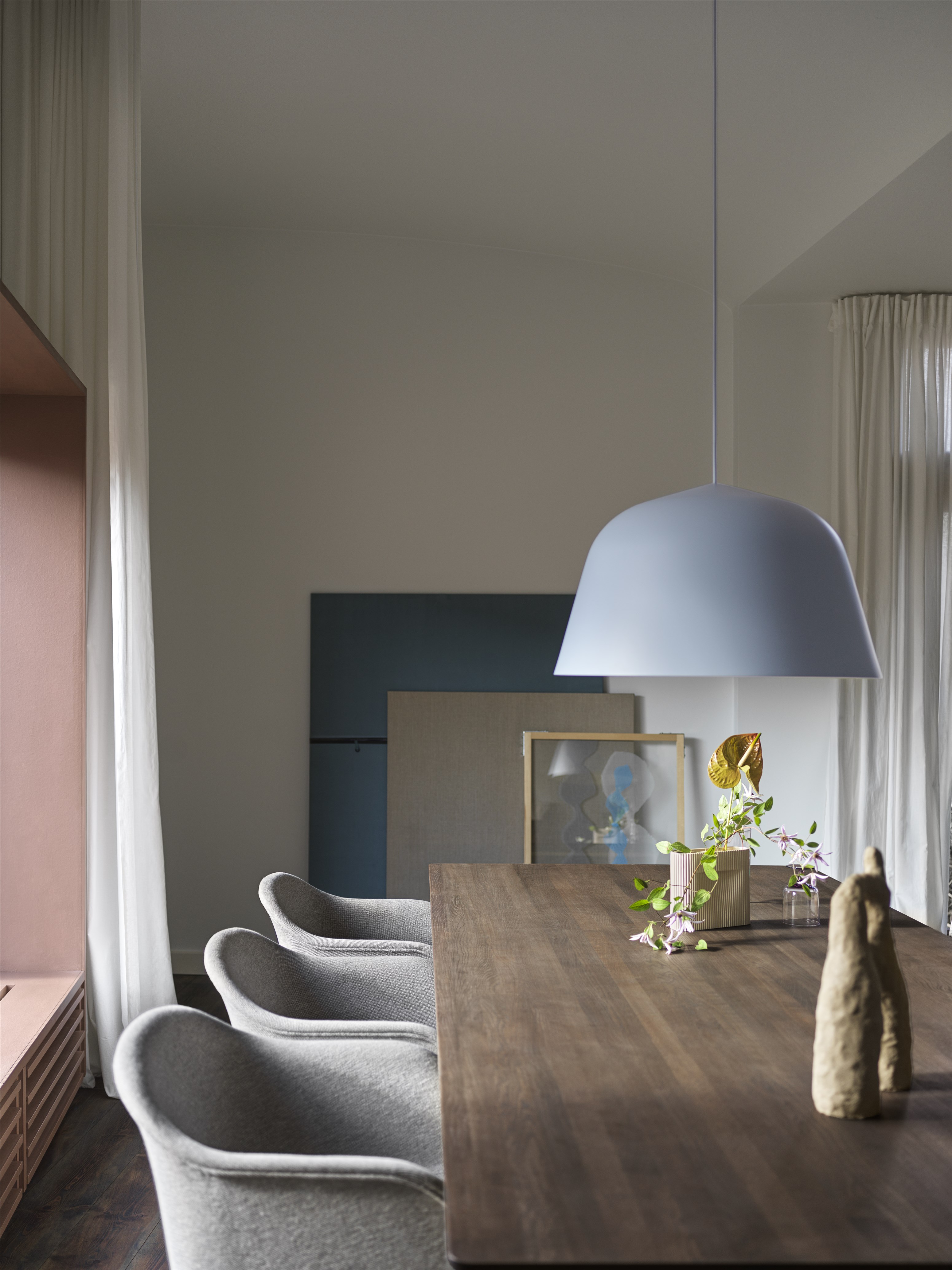Esstisch mit grauen Stühlen und blauer Pendelleuchte, dekoriert mit Skulptur und Blumenvasen für modernes Esszimmer Design.