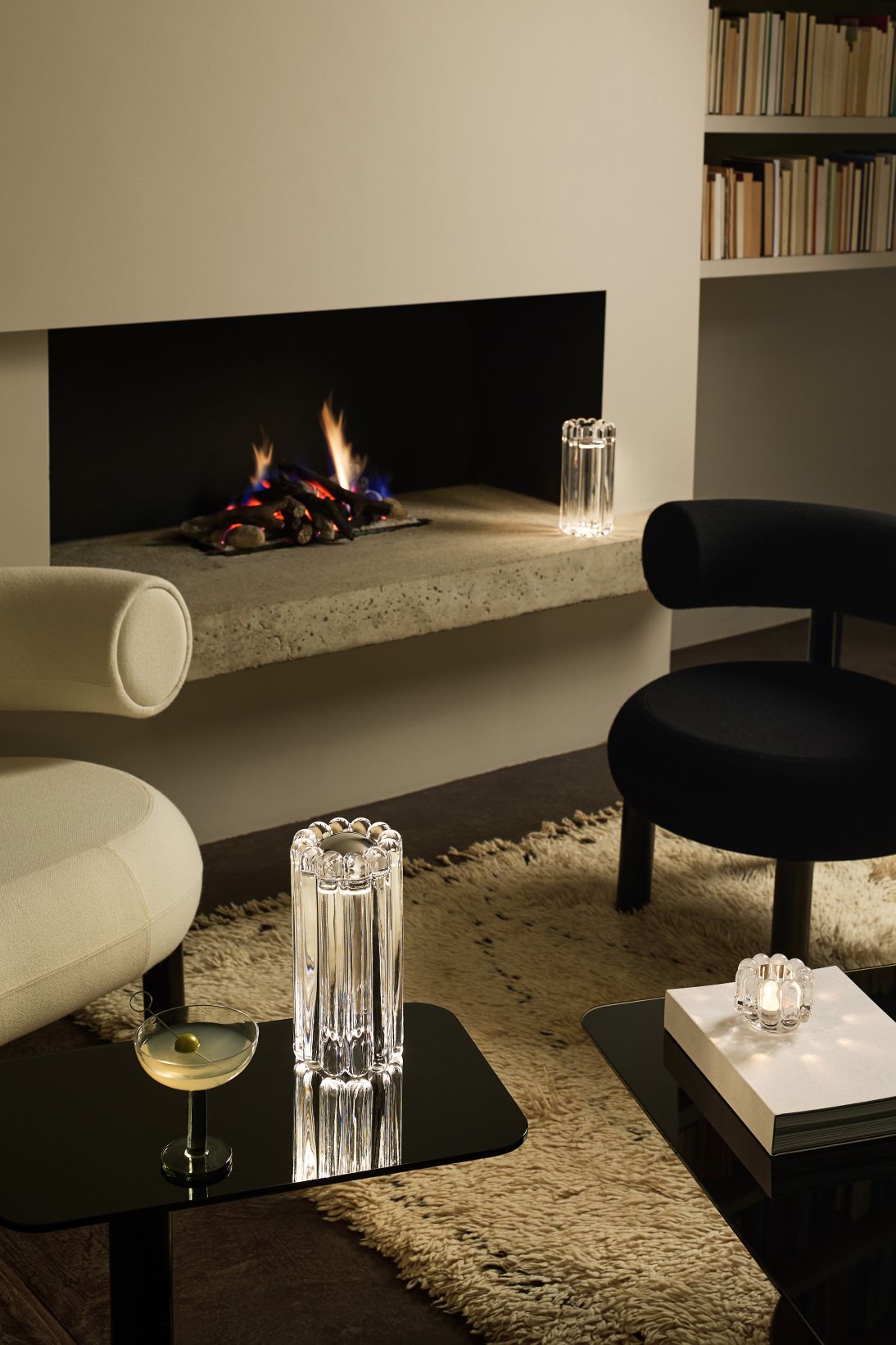 Nahaufnahme der Tom Dixon Press Tischleuchte aus Klarglas in einem stilvollen Wohnzimmer mit Kamin.