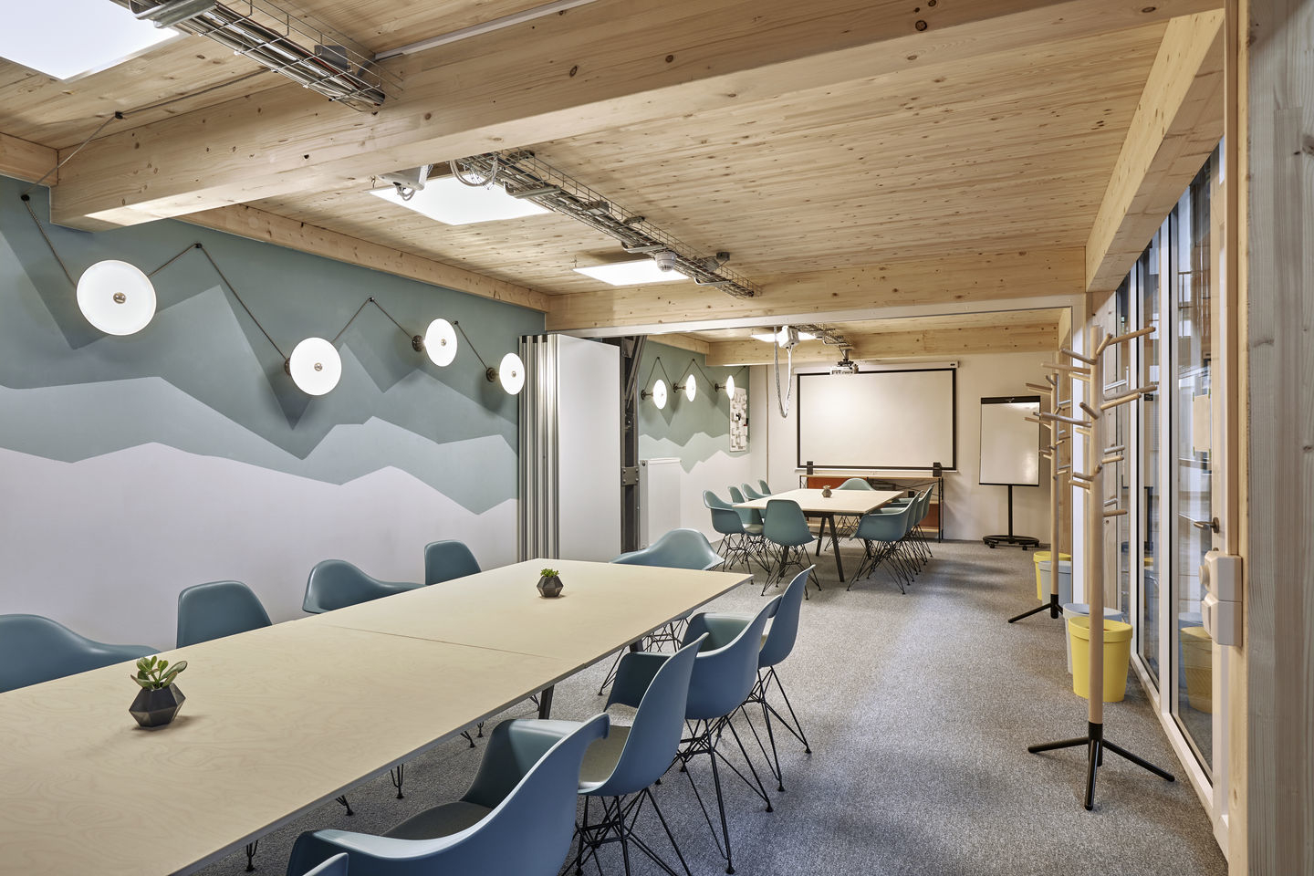 Konferenzraum mit langem Holztisch und blauen Eames Plastic Arm Chairs DAR Stühlen von Vitra.