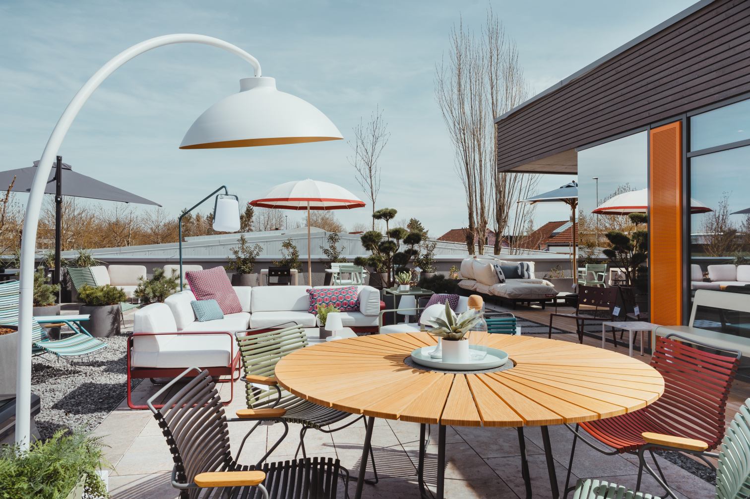 Terrasse mit modernen Gartenmöbeln: Lounge Sofa, Esstisch aus Holz und Design-Stehleuchte.