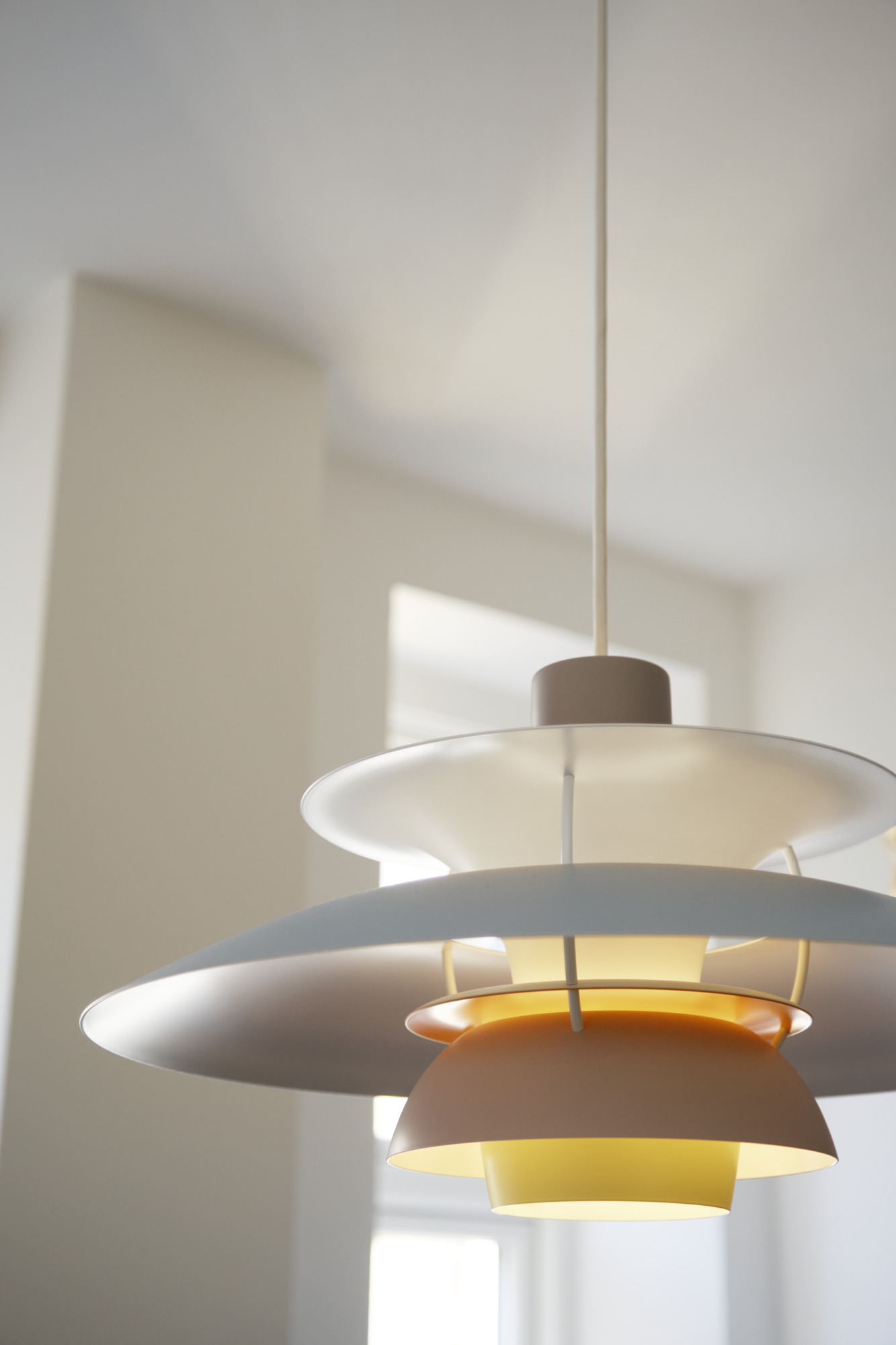 Nahaufnahme der PH 5 Pendelleuchte von Louis Poulsen in Weiß- und Gelbtönen, modernes Design.