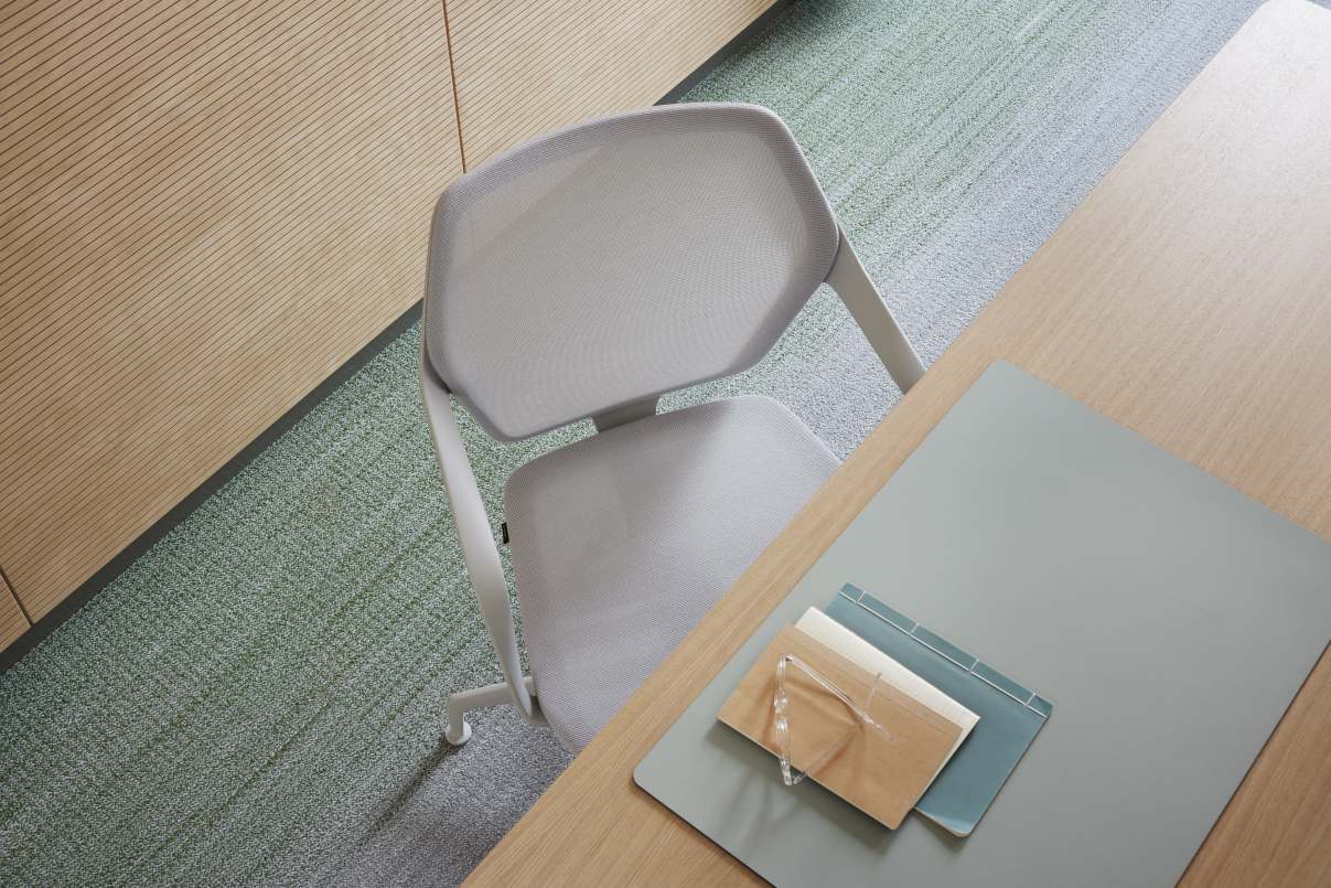 Ray Work 9220 Bürodrehstuhl von Brunner, hellgrau, mit Netzrückenlehne und Schreibtisch mit Büromaterialien von oben.